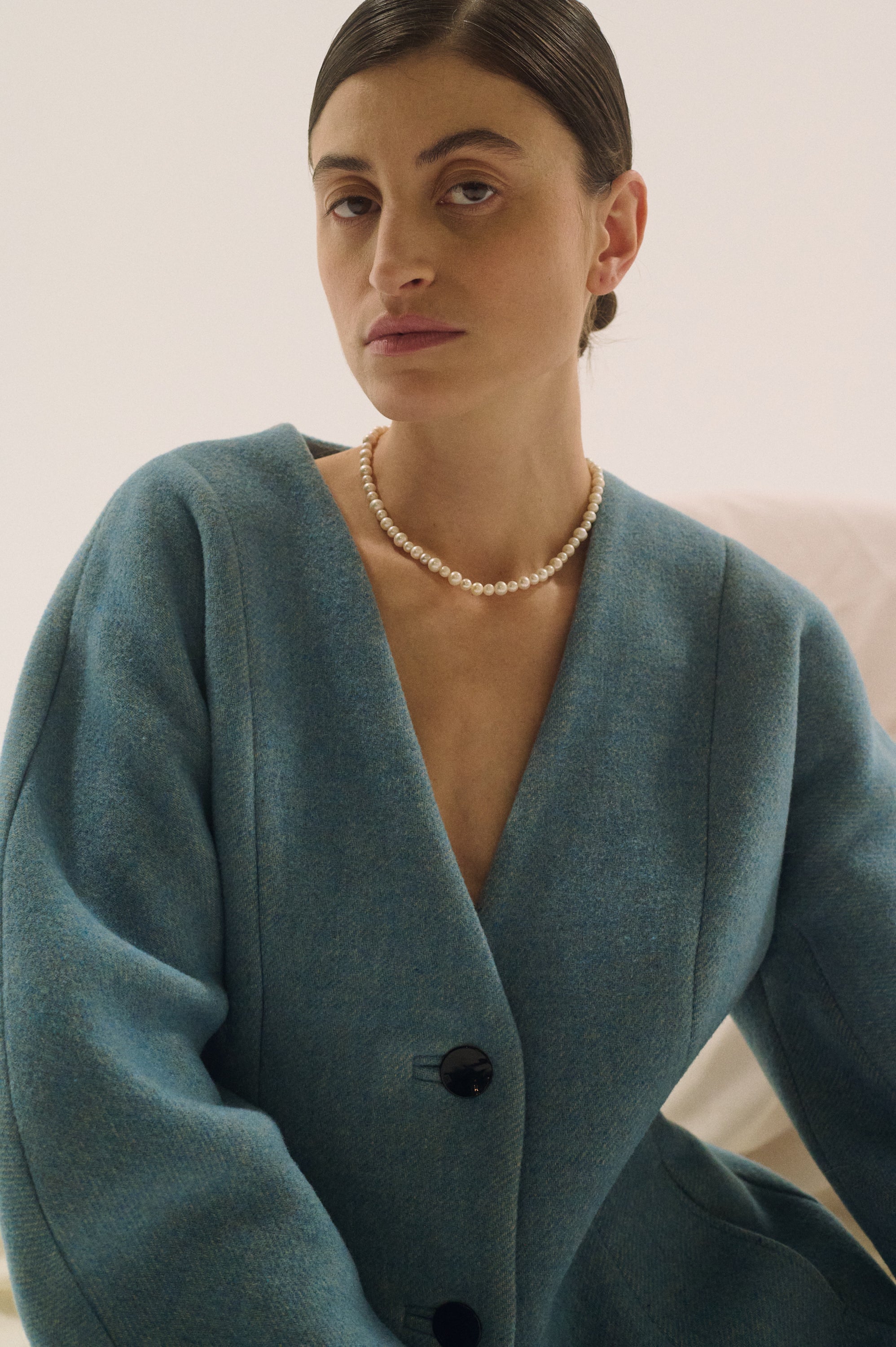 Elegant woman styling round pearl necklace close-up – UGNÈS STORY