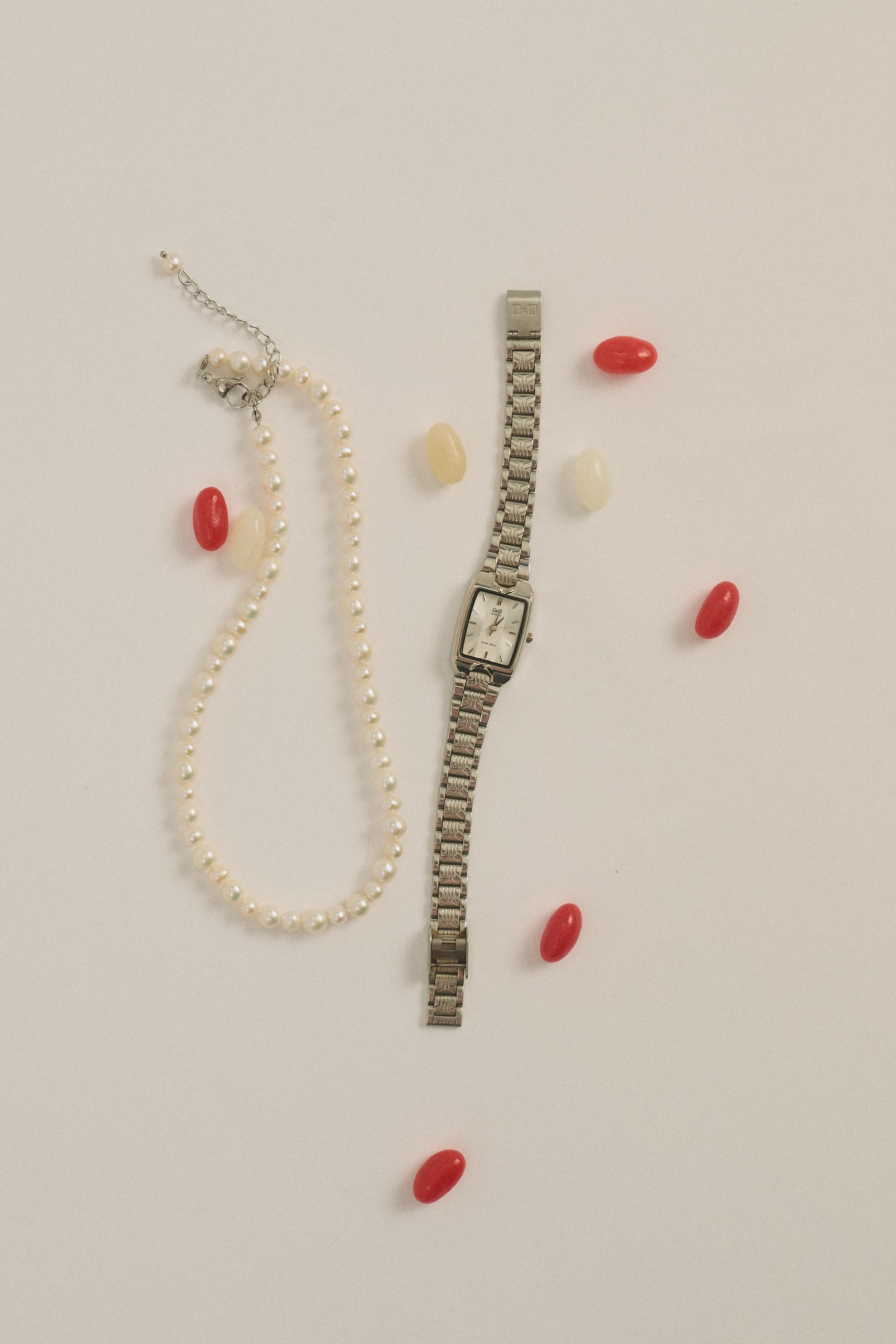 Flat lay of round pearl necklace with silver watch – UGNÈS STORY