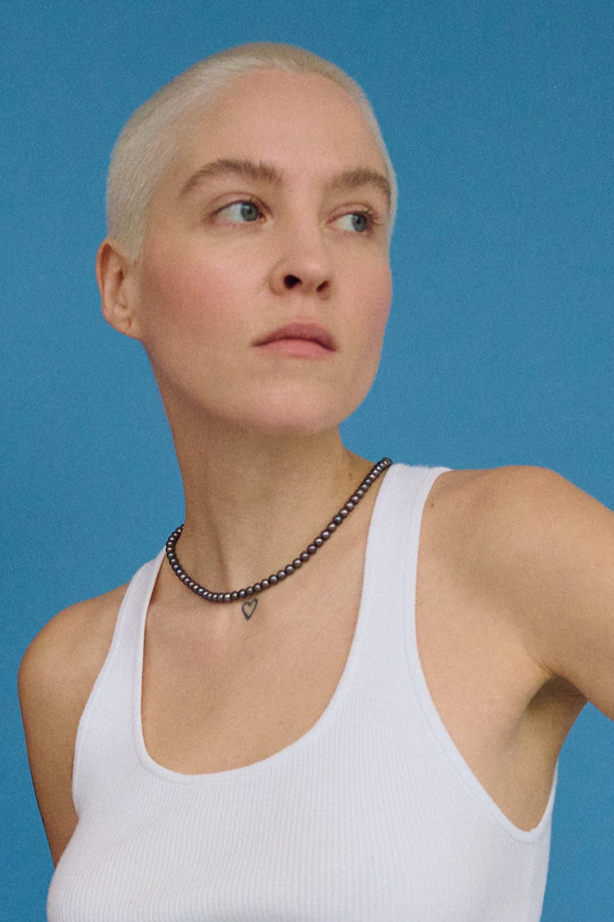 Dark freshwater pearl necklace for women styled with a blue background