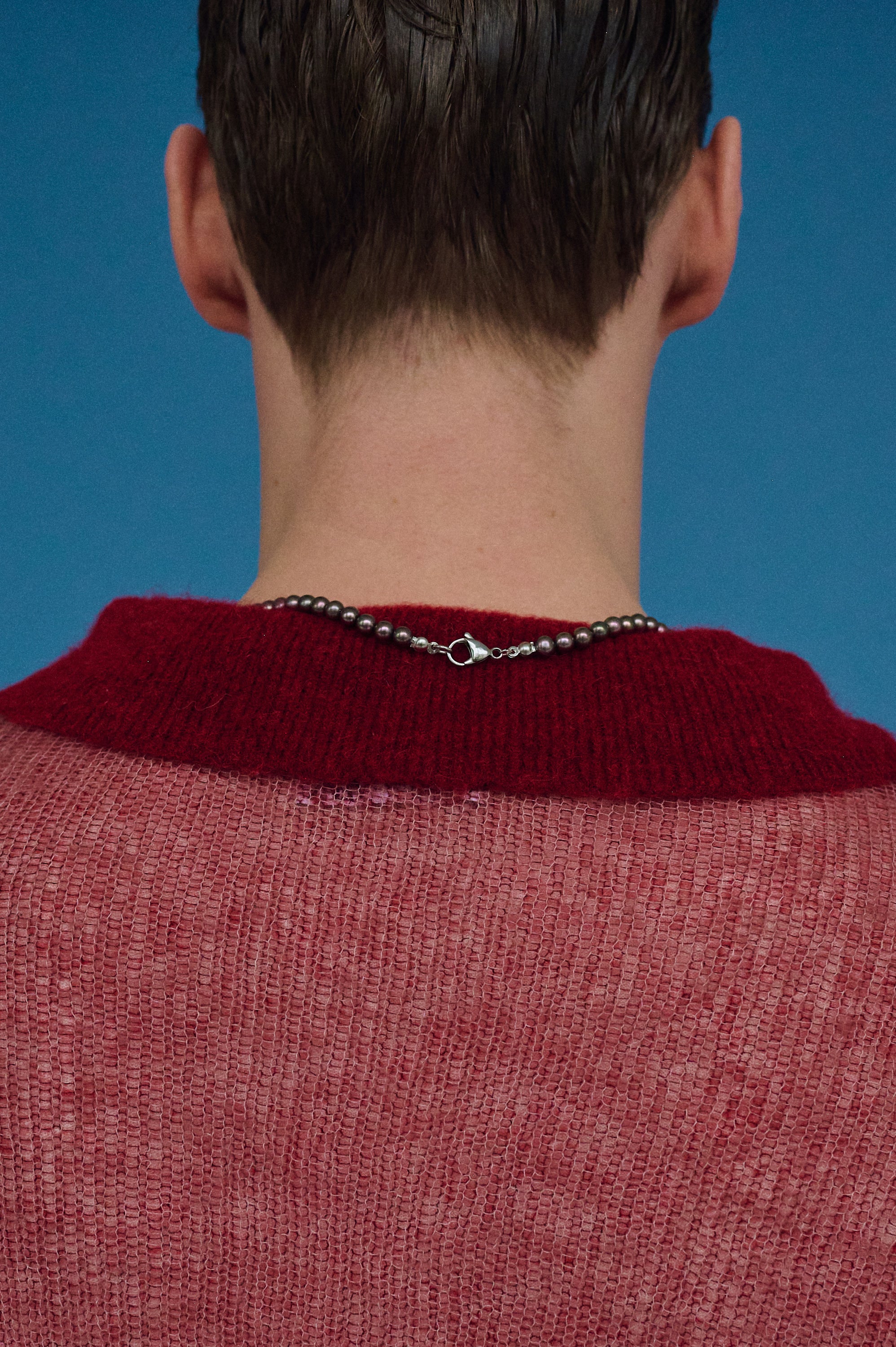 Close-up of men’s brown pearl necklace with silver clasp.