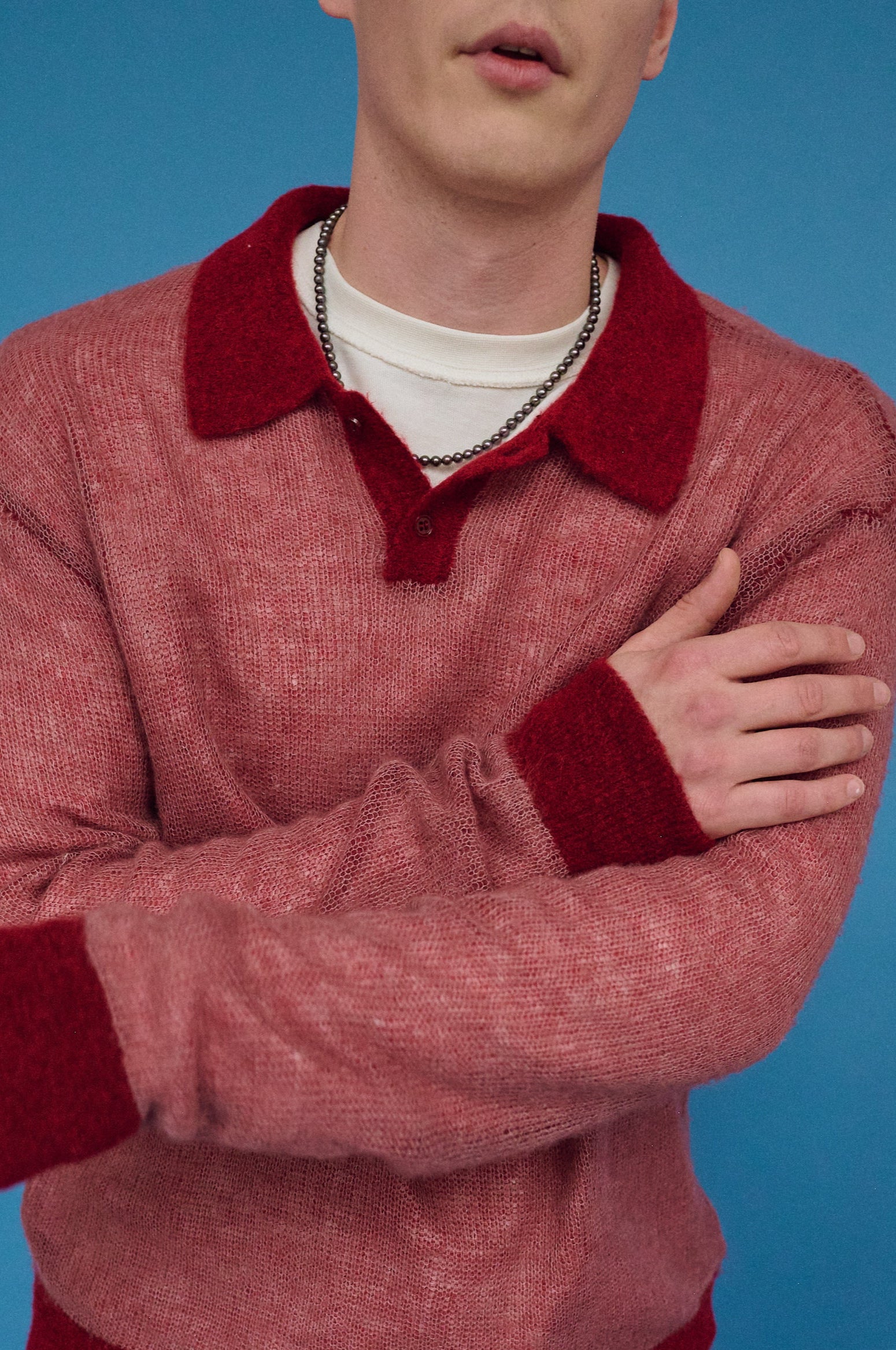 Stylish men’s dark pearl choker with red sweater outfit.