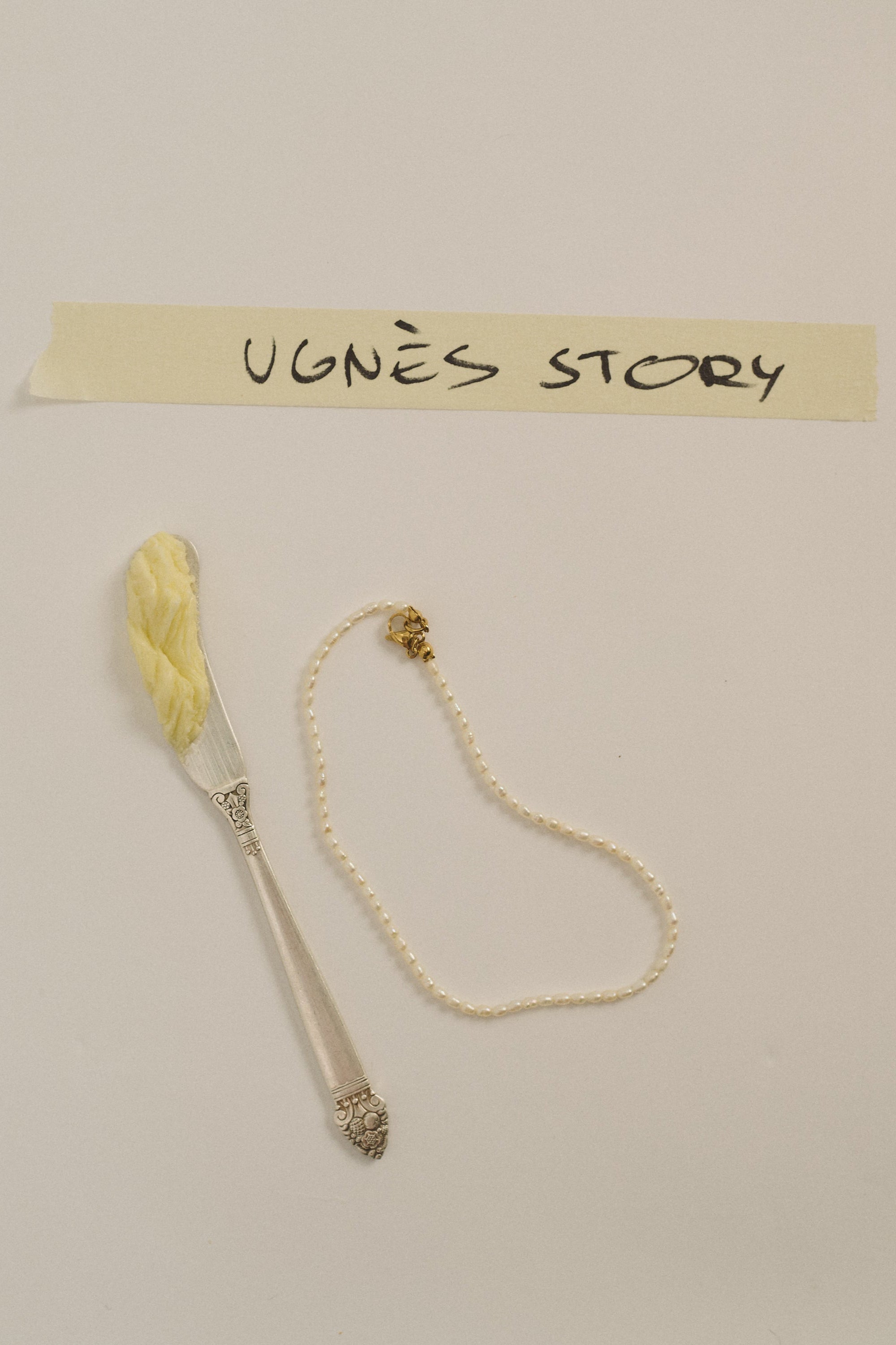 Delicate tiny pearl choker necklace with gold clasp on neutral background