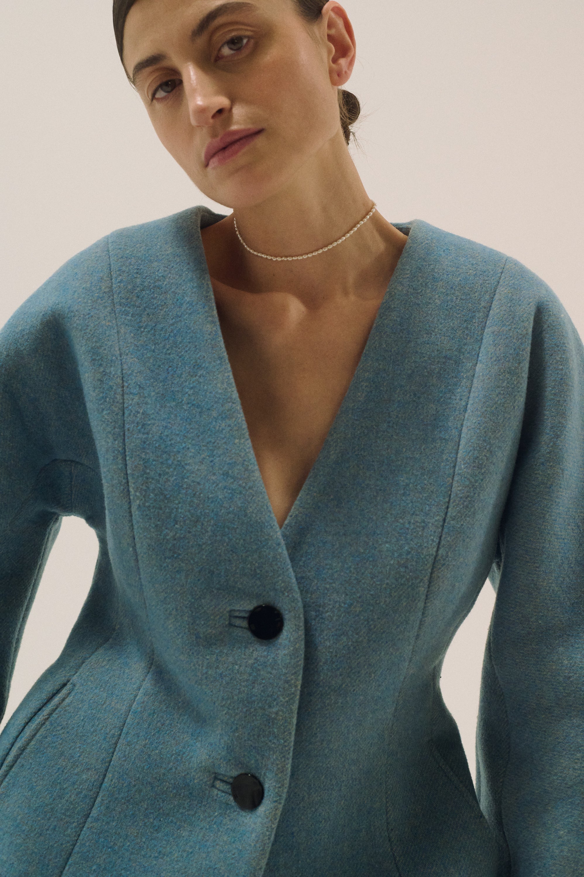 Model wearing delicate tiny freshwater pearl choker with blue blazer
