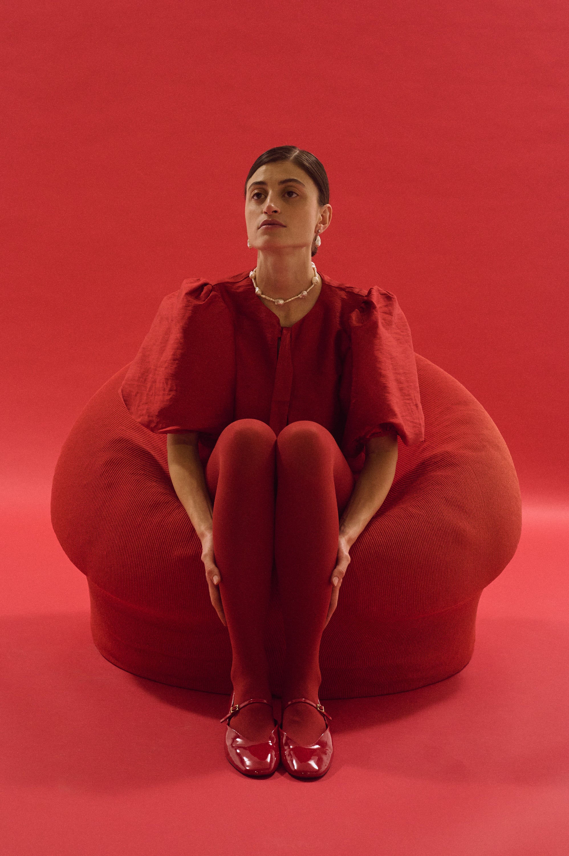 Full-body view of model in red dress styled with fitted baroque and stick pearl necklace