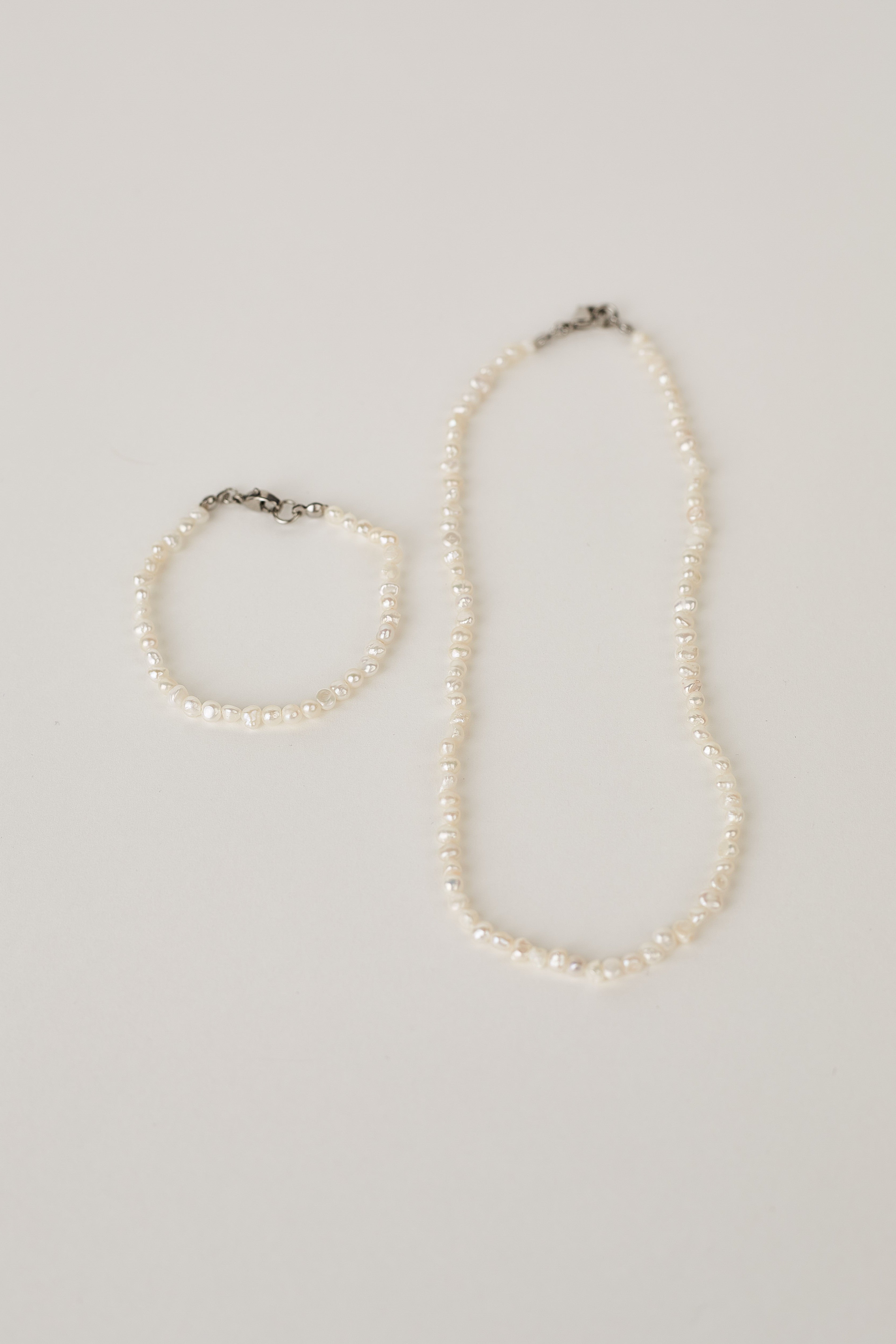 Pearl necklace and bracelet on a light gray background