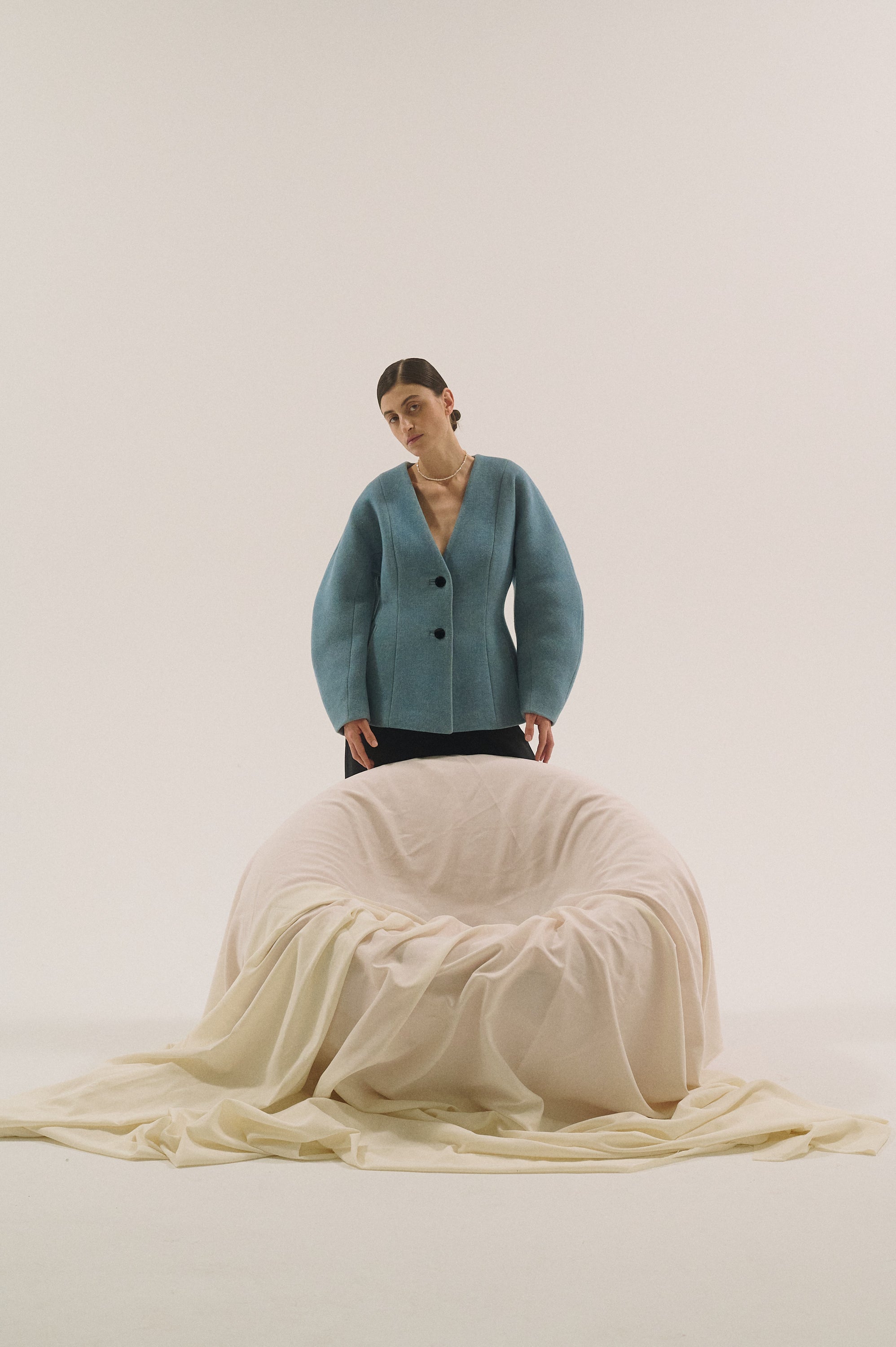 Minimal pearl necklace close-up styled with a structured blue jacket.