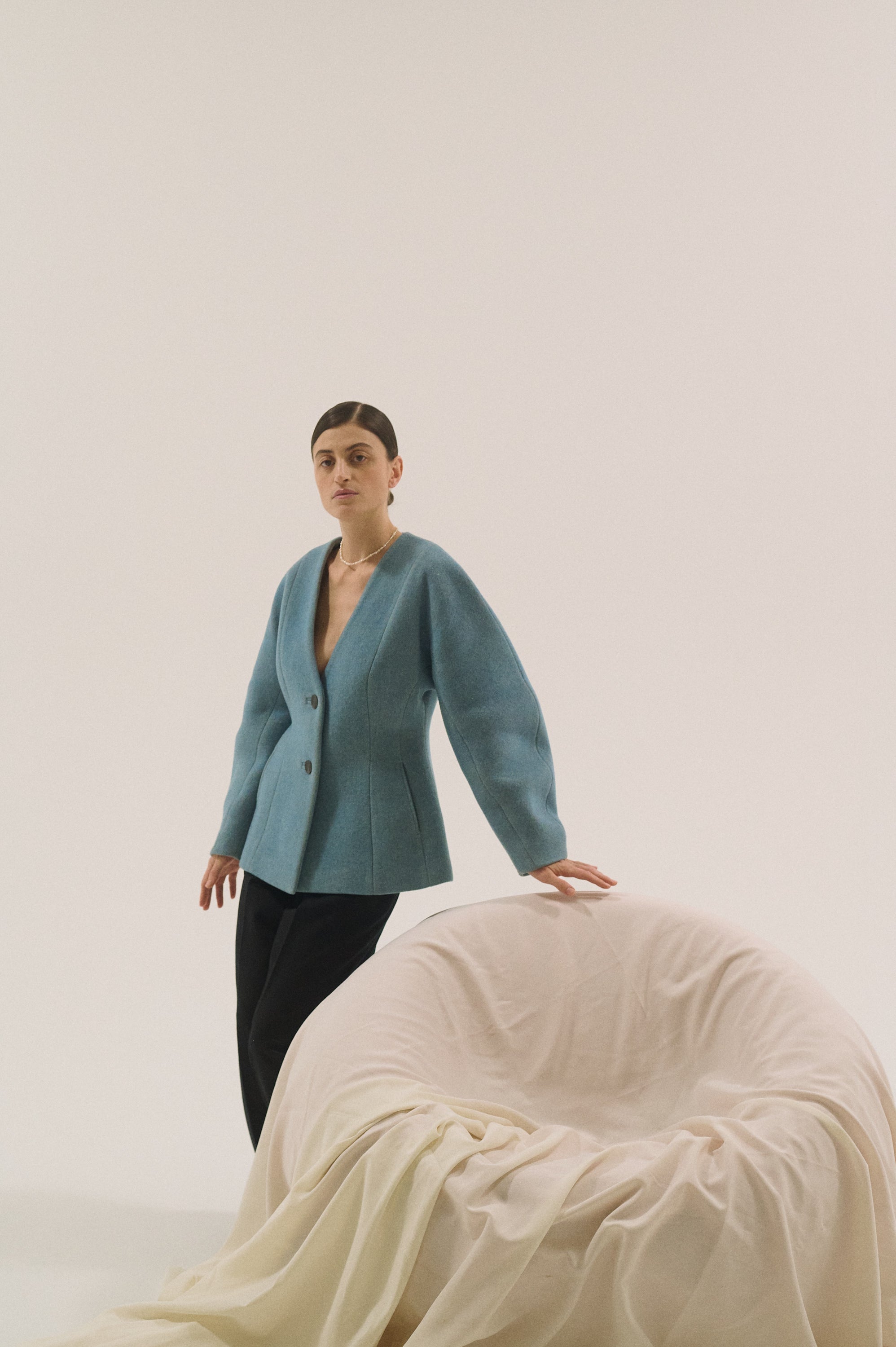 Woman wearing a minimal freshwater pearl necklace styled with a blue blazer.