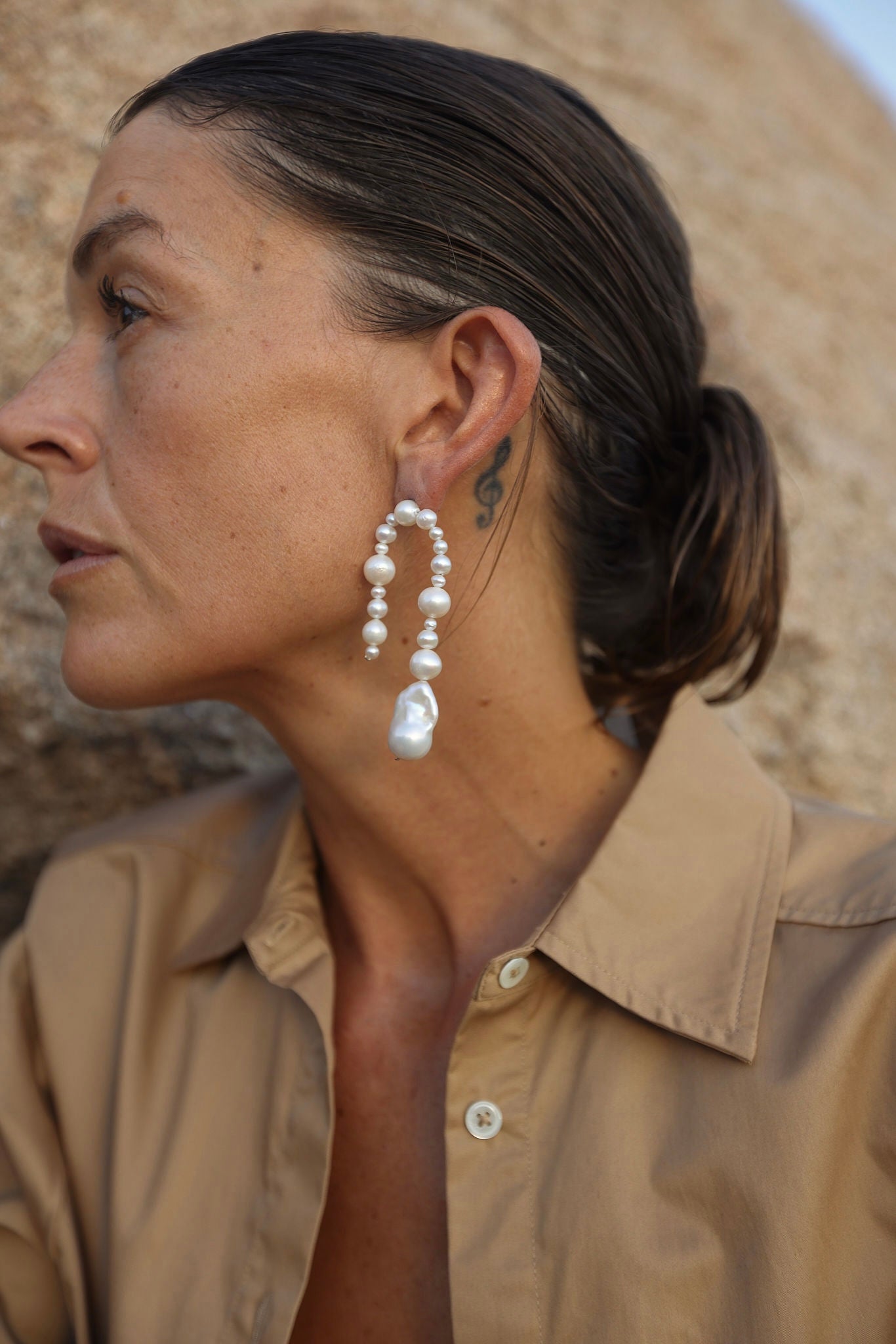 Close-up of bold pearl dangle statement earrings with baroque drop