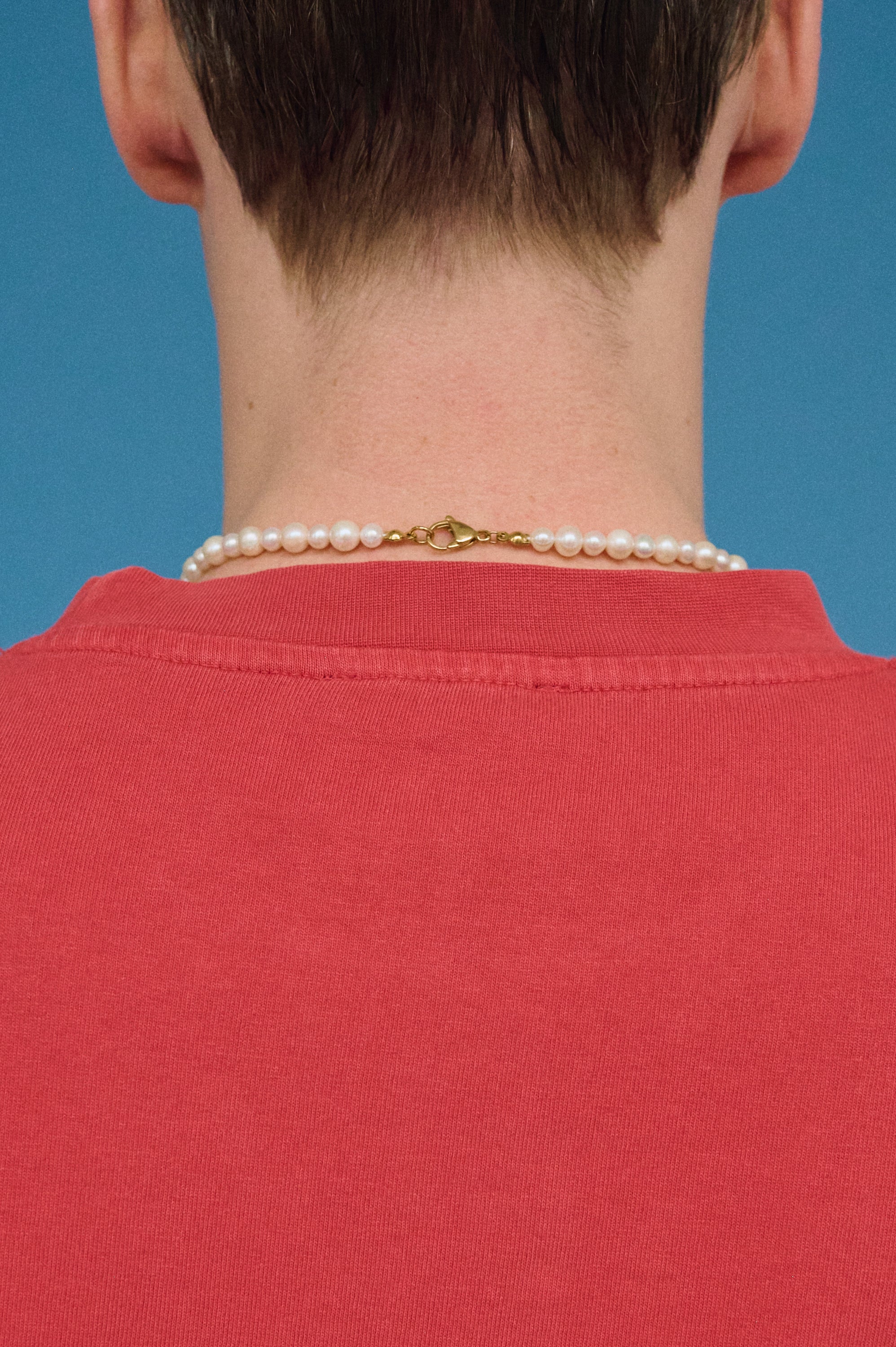 Back view of a men’s real white pearl necklace with gold clasp.