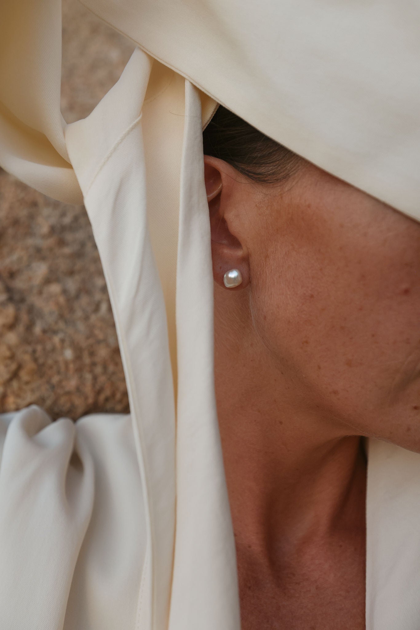 Close-up of natural Keshi pearl stud earrings on model outdoors