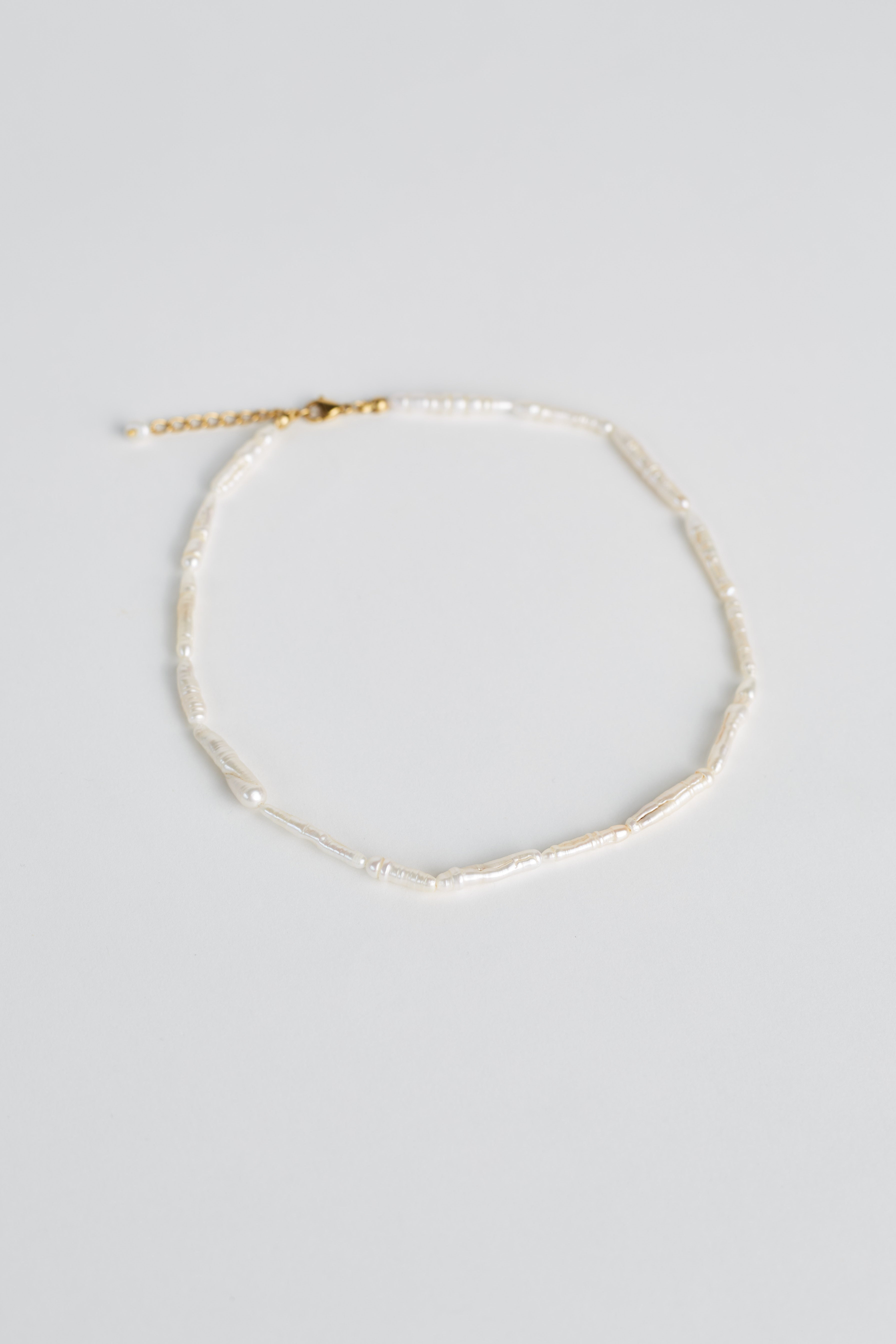 Gold necklace on a light gray background