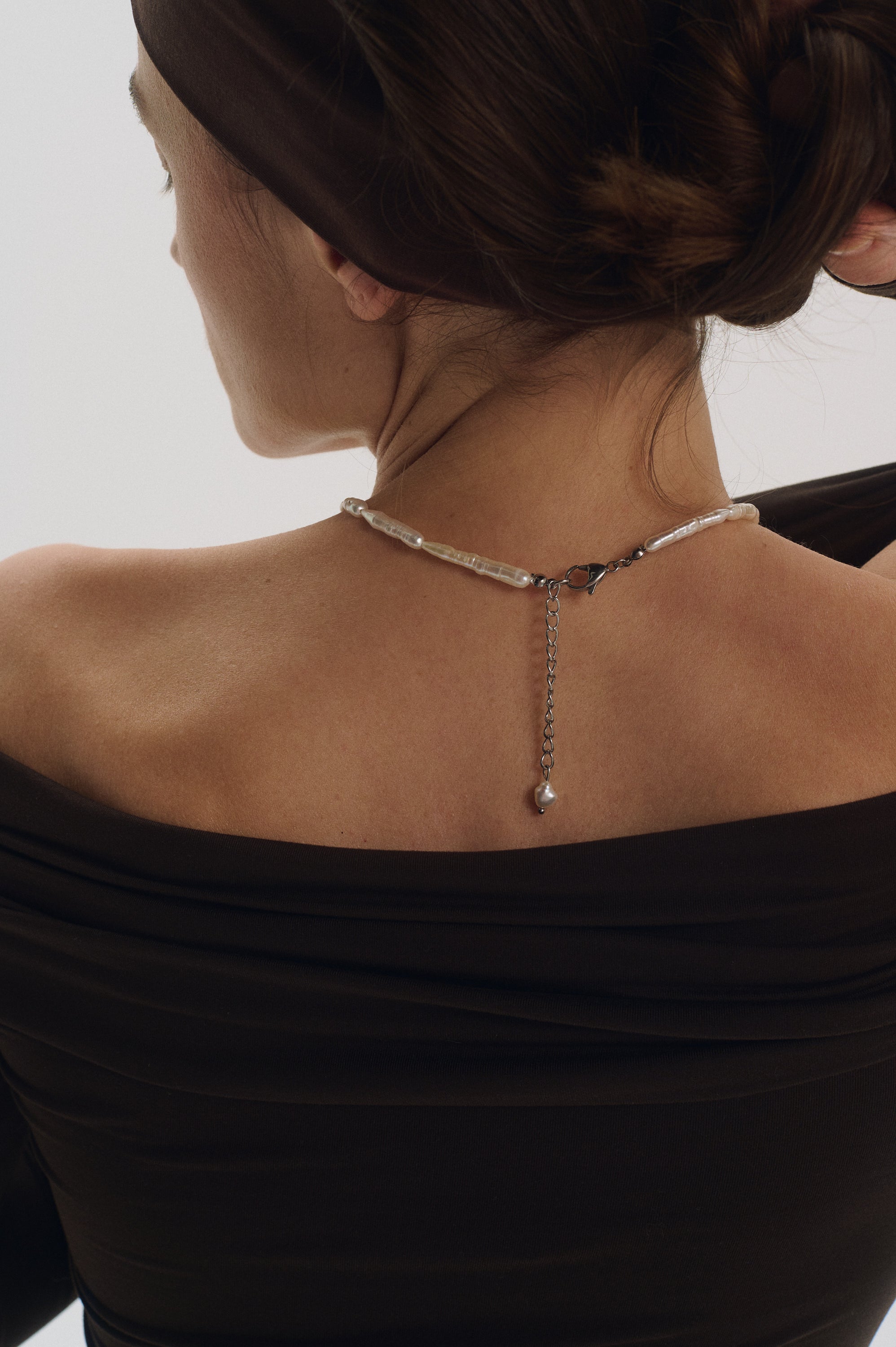 Front close-up of model wearing elongated freshwater stick pearl necklace.