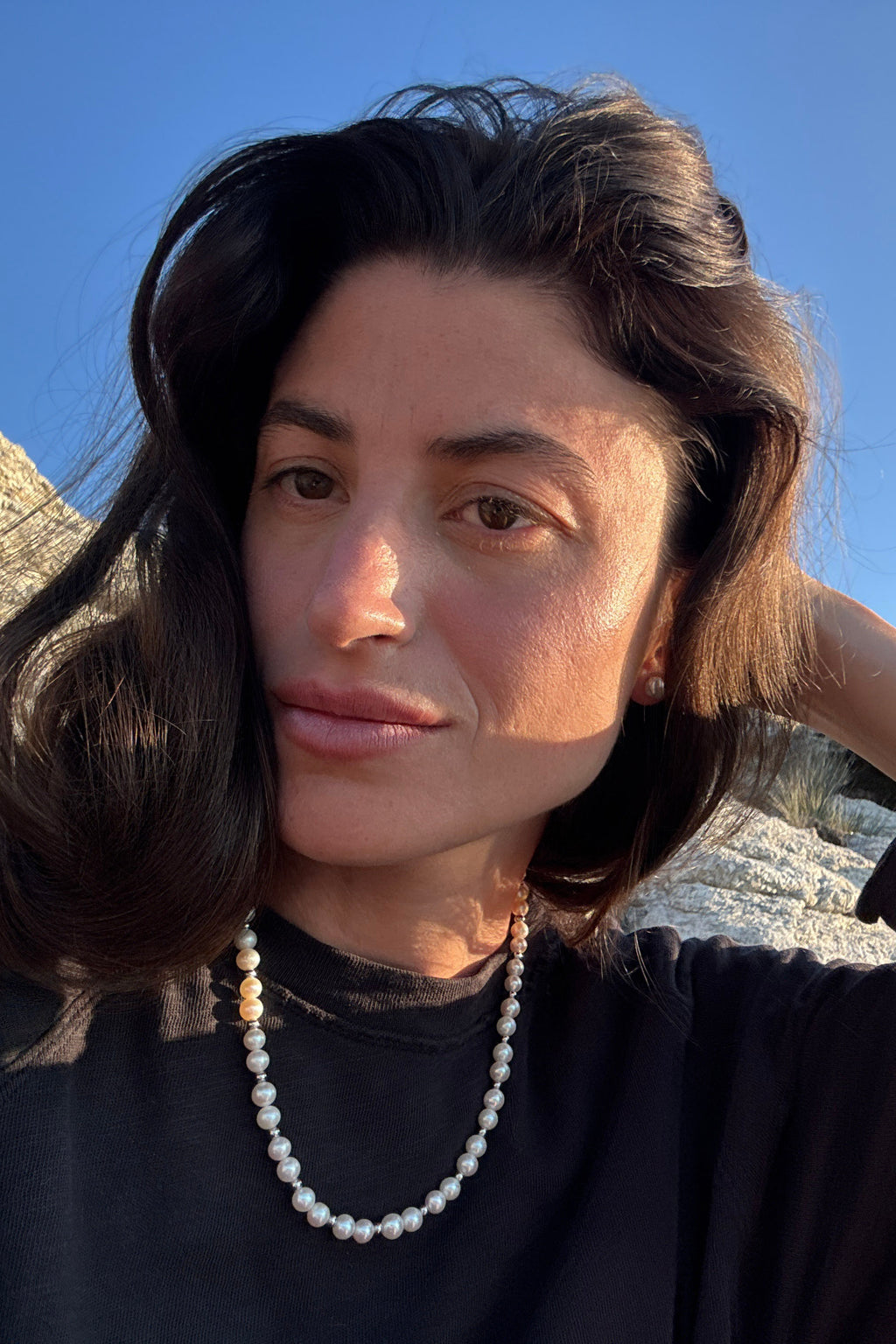 Woman wearing a classic white freshwater pearl necklace with subtle metal bead accents.