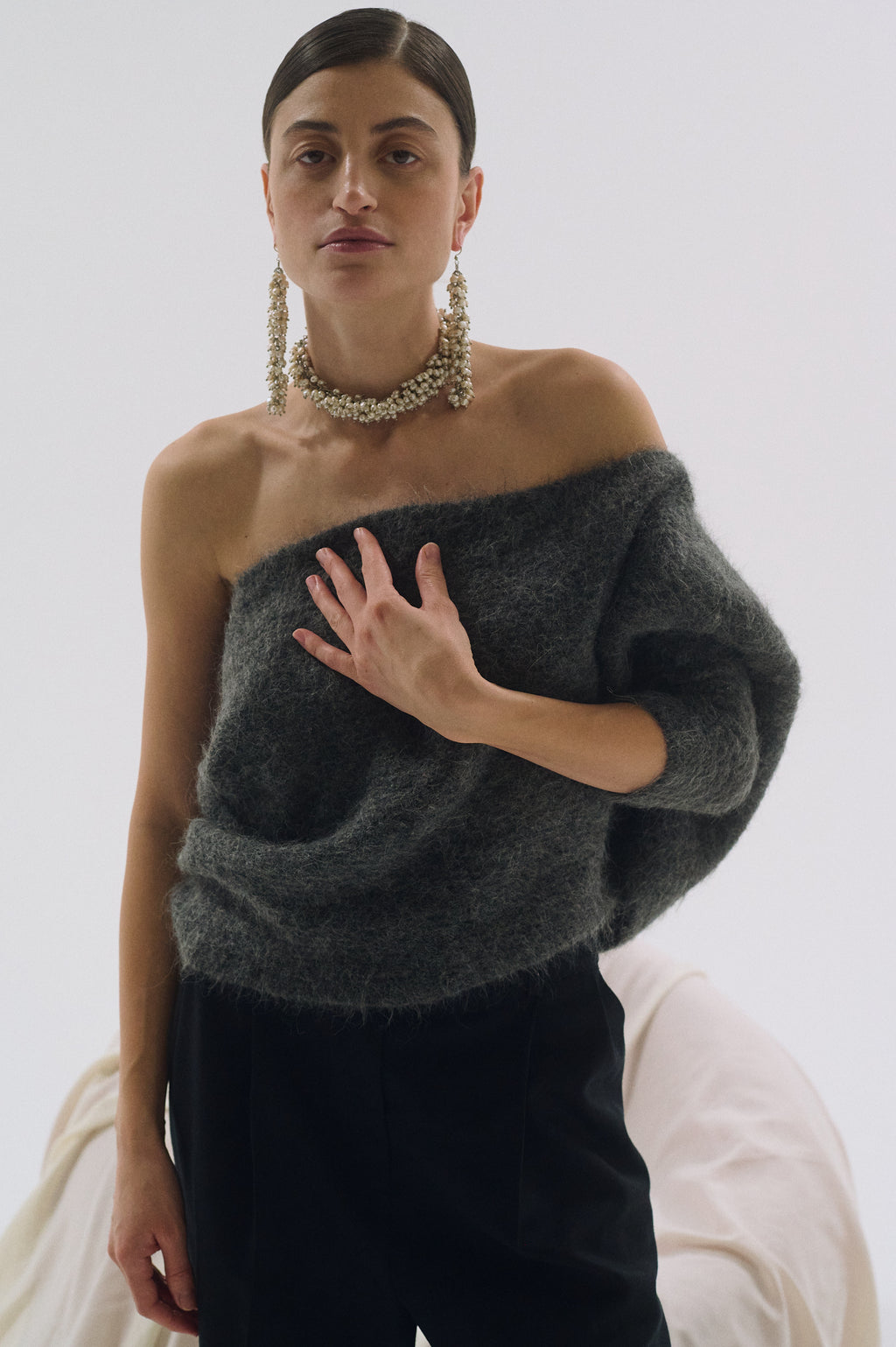 Woman wearing long bold statement pearl earrings with grey sweater