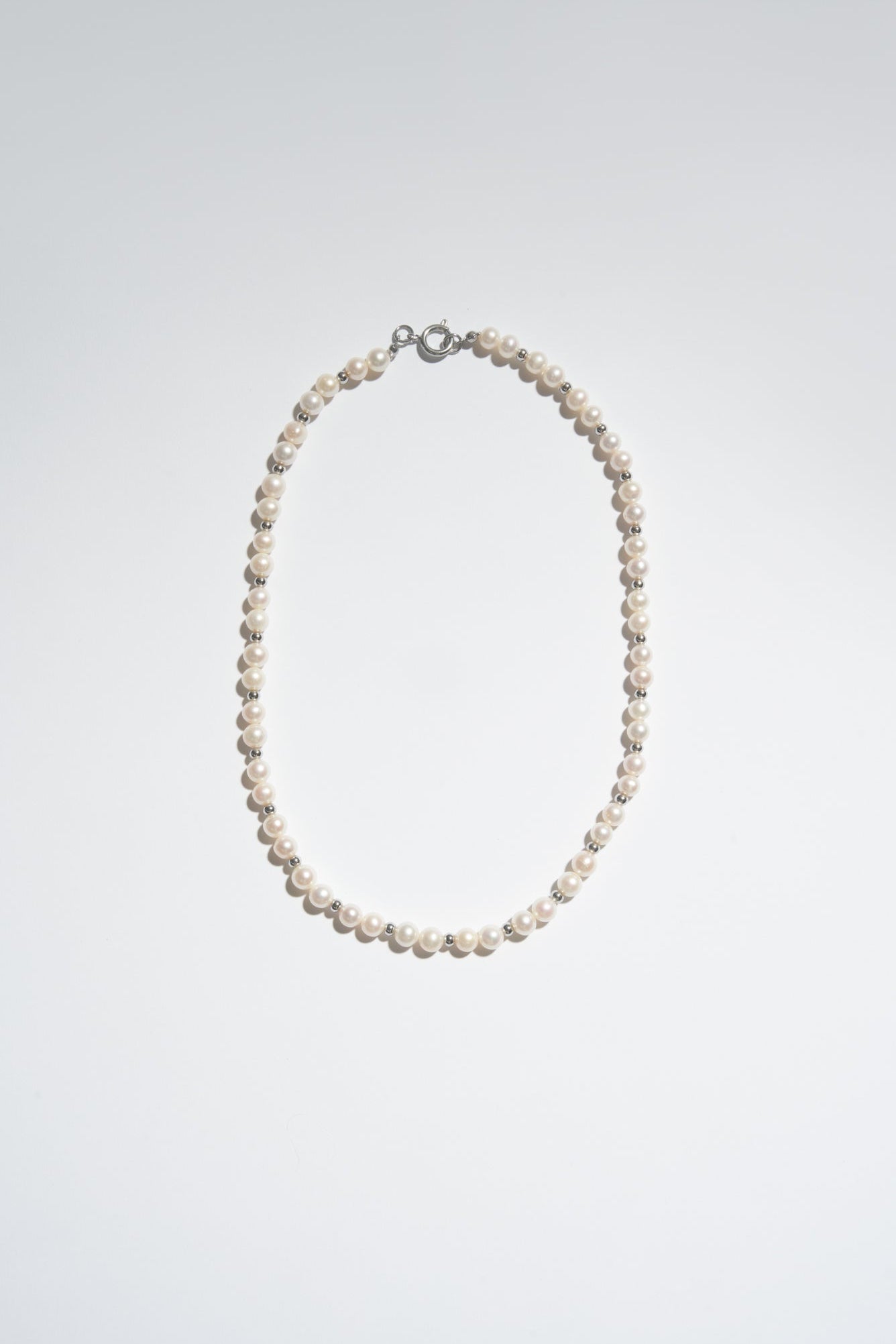 Classic freshwater pearl necklace made with round white pearls and small metal beads.