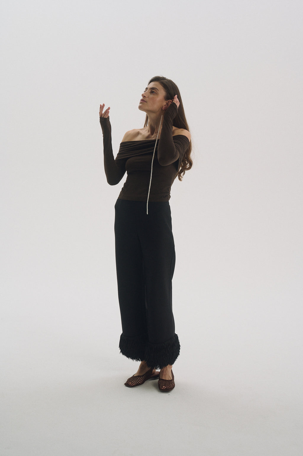 Model putting on single long dangling freshwater pearl earring