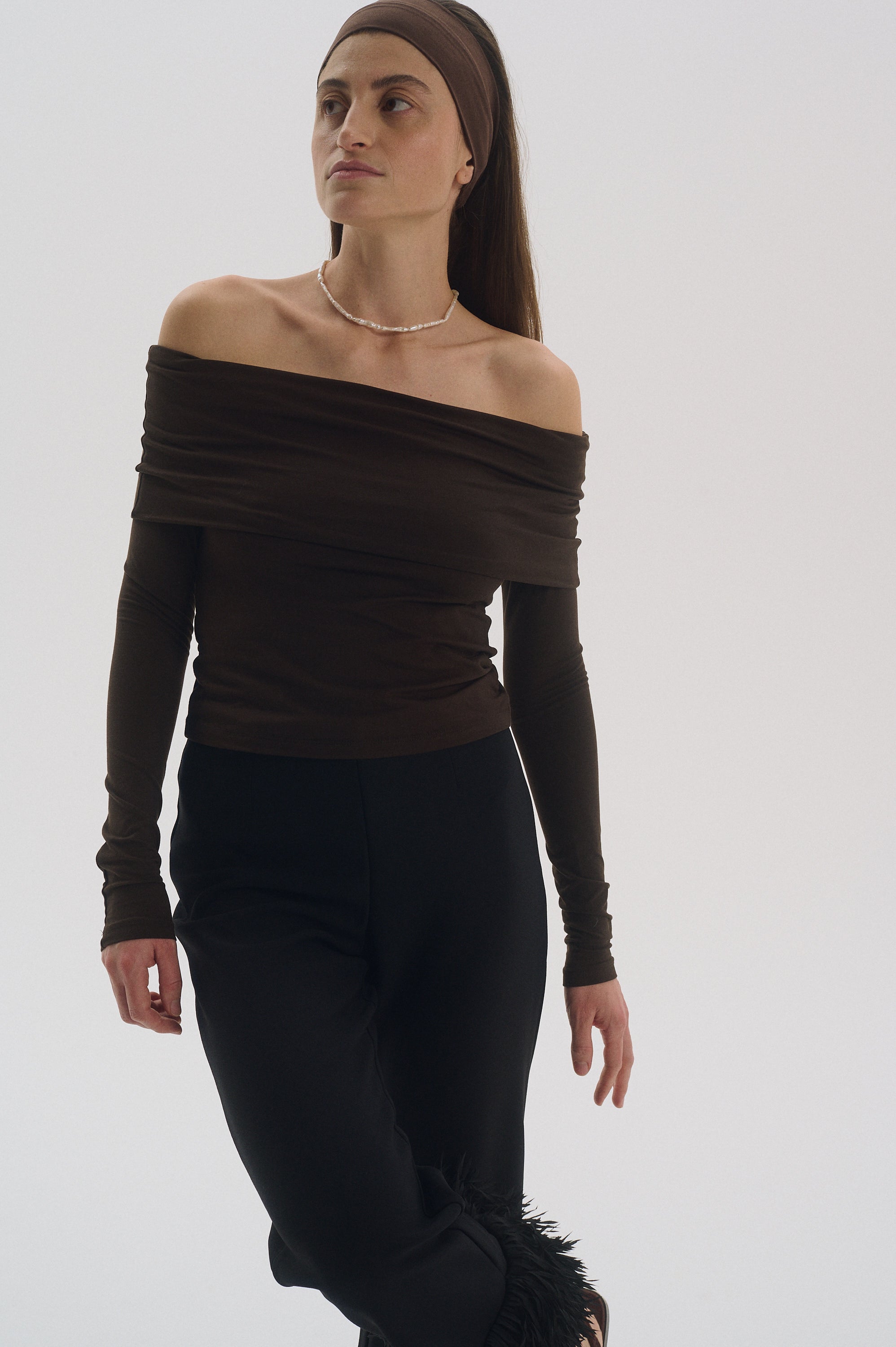 Full body look featuring stick pearl choker styled with black pants and brown top.