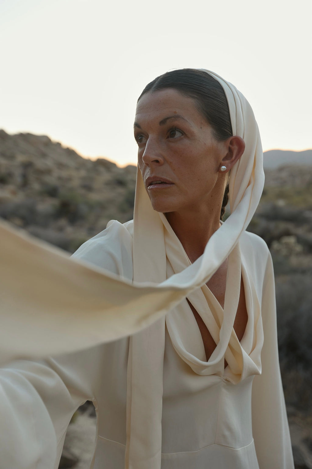 Woman in a white outfit with natural pearls stud earrings in a desert landscape