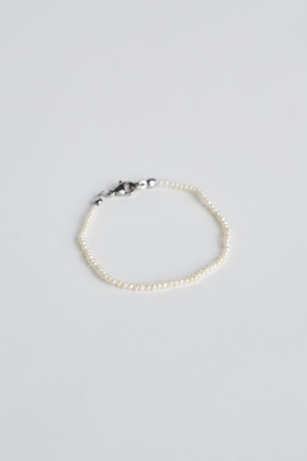 Tiny pearl bracelet with silver clasp on white background