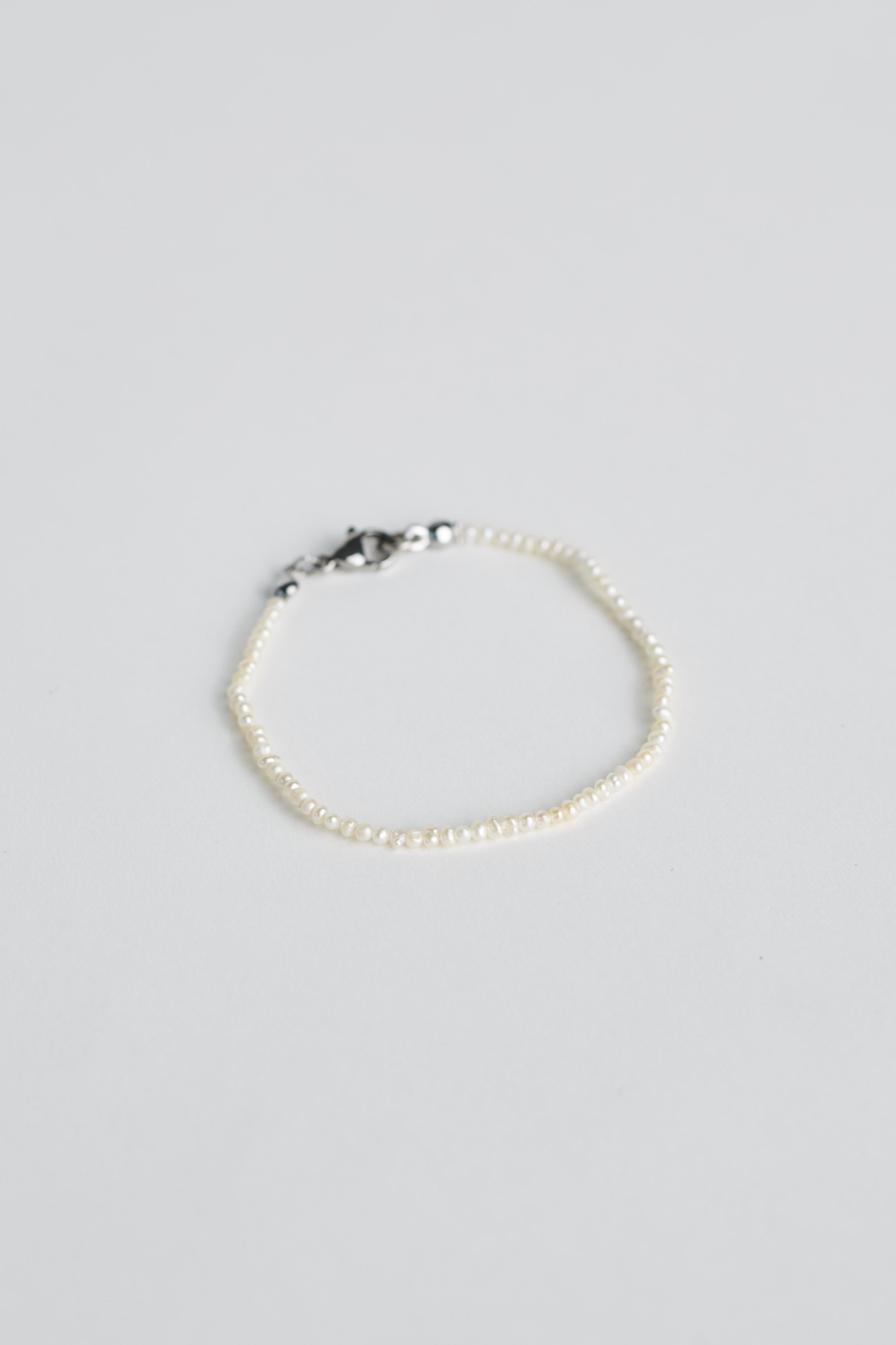 Tiny pearl bracelet with silver clasp on white background