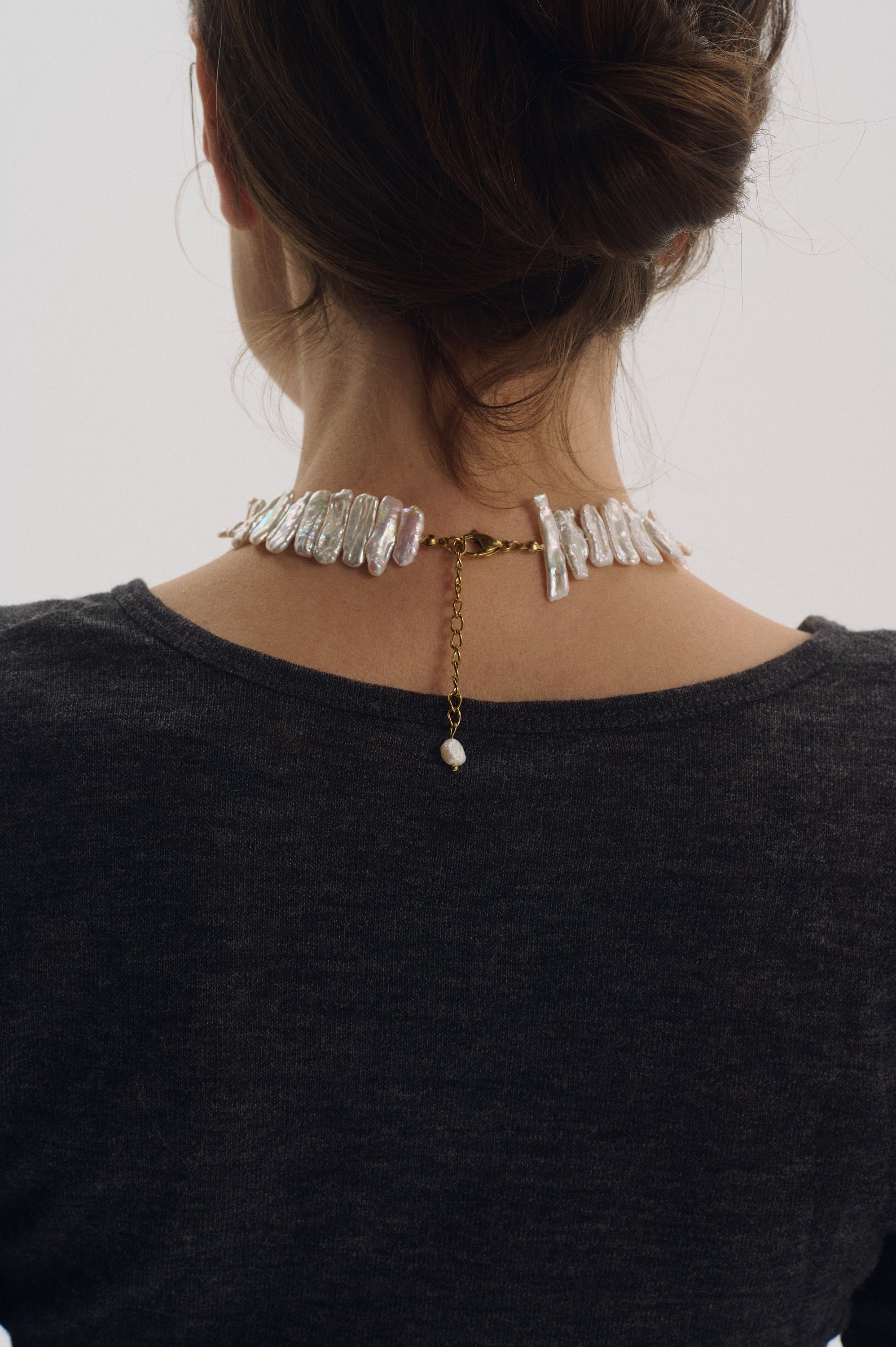 Close-up of white Keshi pearl choker necklace with gold clasp.