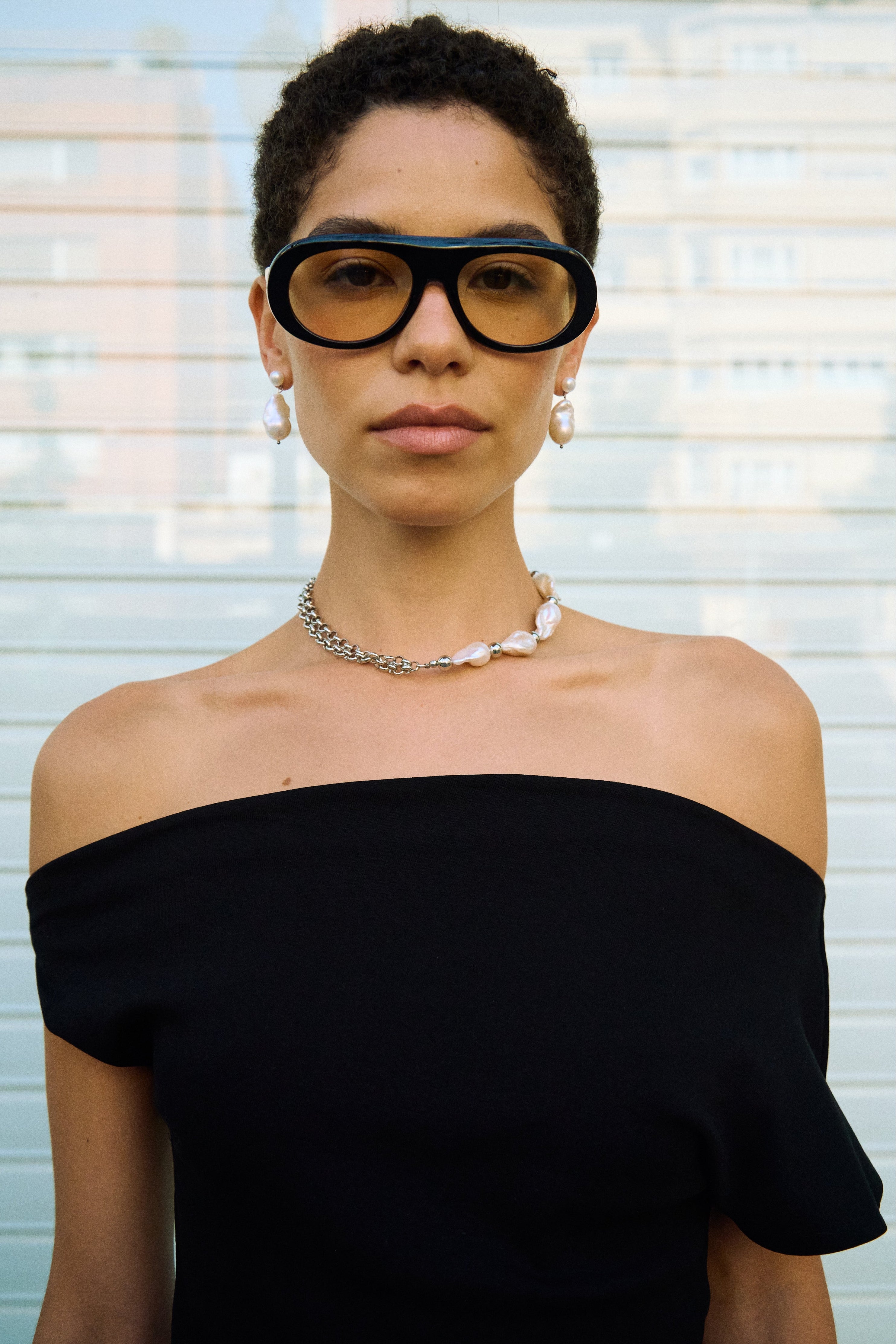 Model wearing baroque pearl drop earrings with a small button pearl and a larger freshwater pearl drop.
