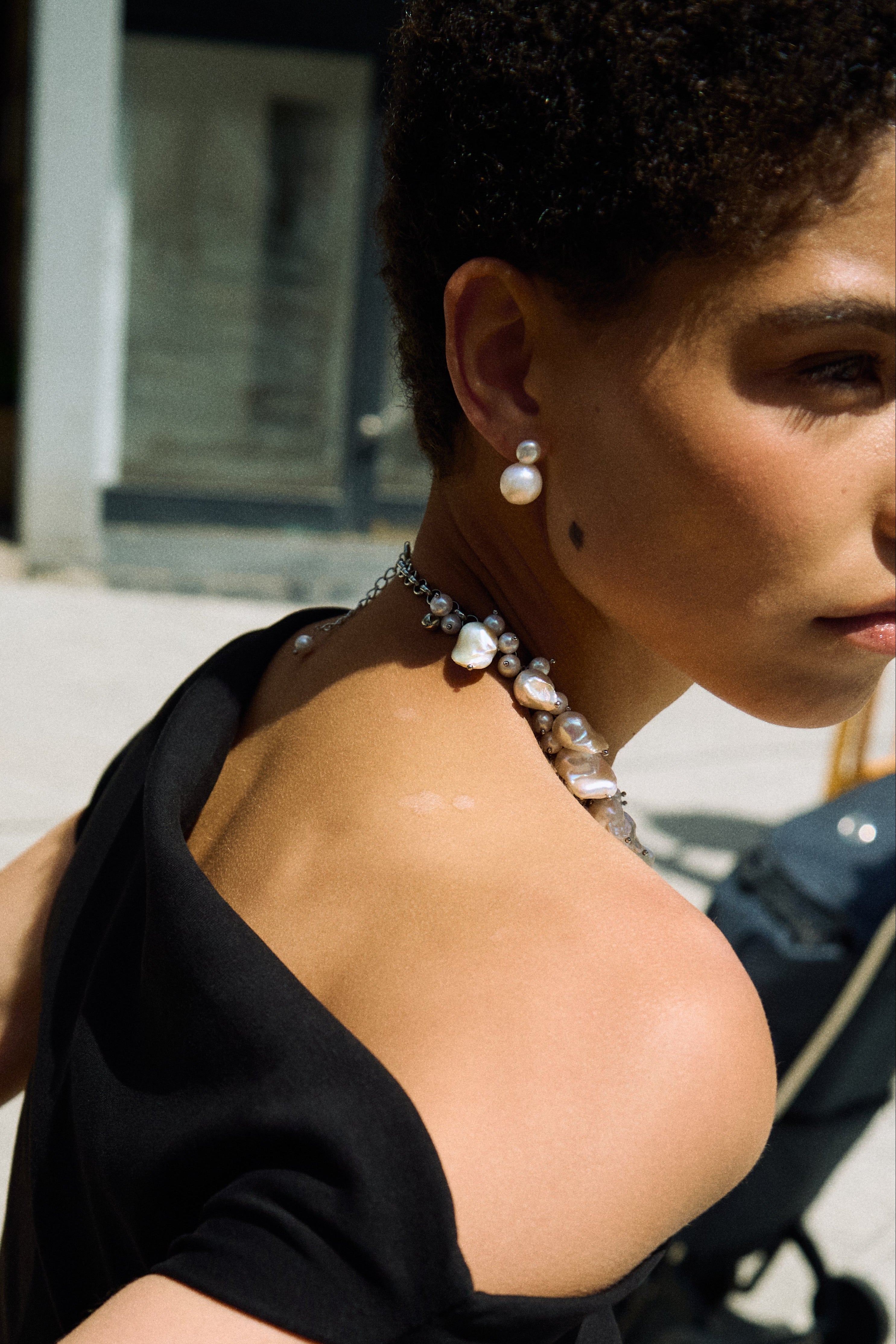 Close-up of double pearl stud earrings with one small button pearl and one larger freshwater pearl.