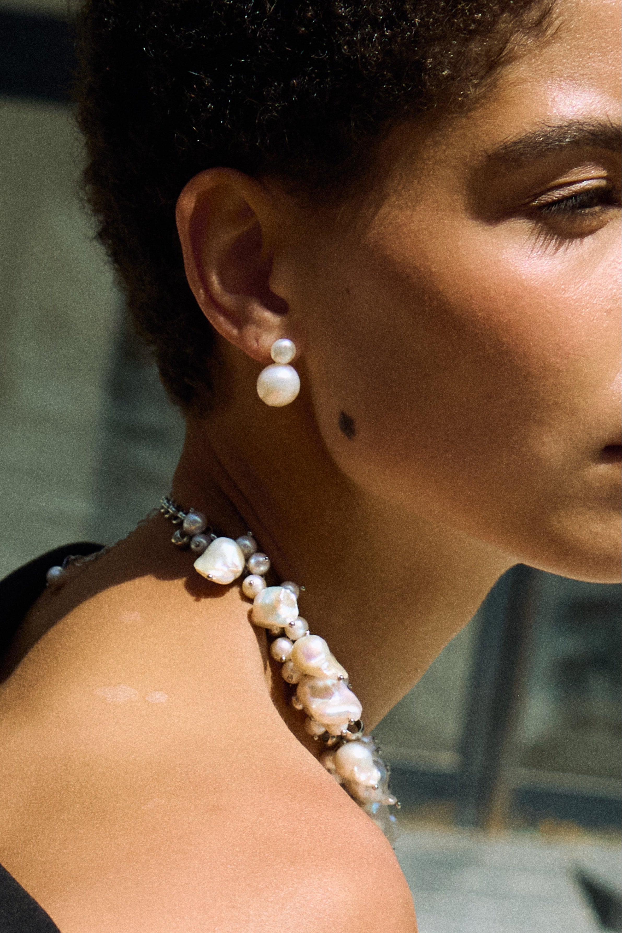 Model wearing double pearl stud earrings made from two natural freshwater pearls.