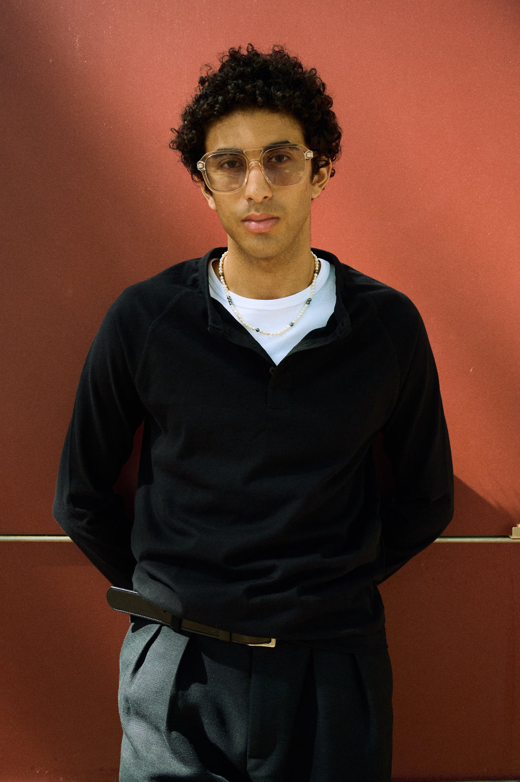 Men’s peacock pearl necklace styled with a white T-shirt and black top.