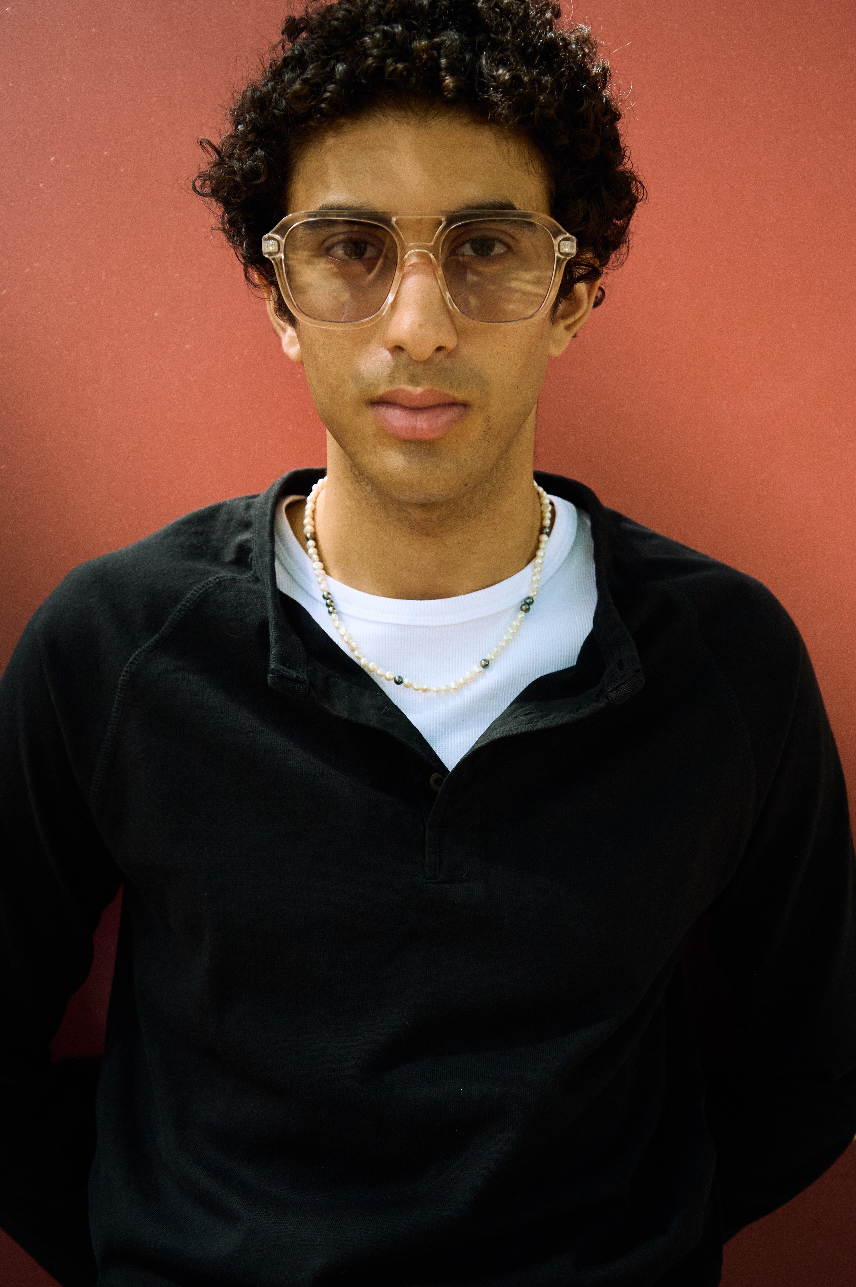 Man wearing a men’s pearl necklace made with white nugget freshwater pearls and dark brown peacock pearls.