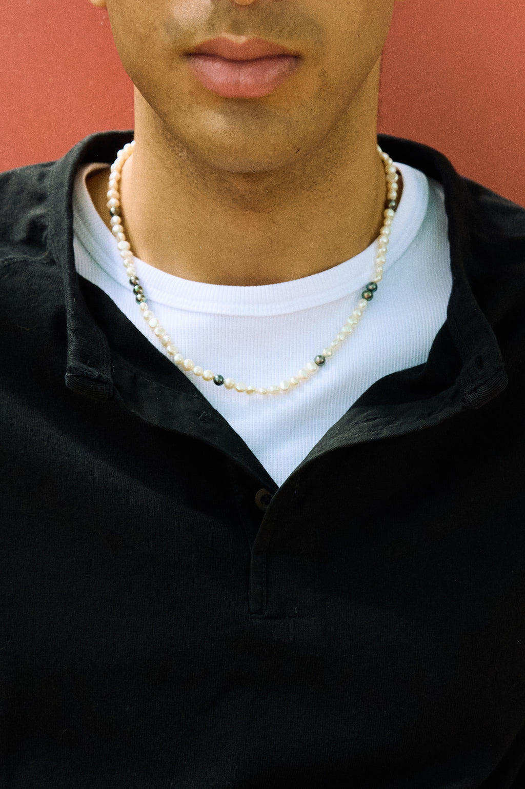 Close-up of a men’s pearl necklace with white nugget pearls and dark peacock pearl accents.