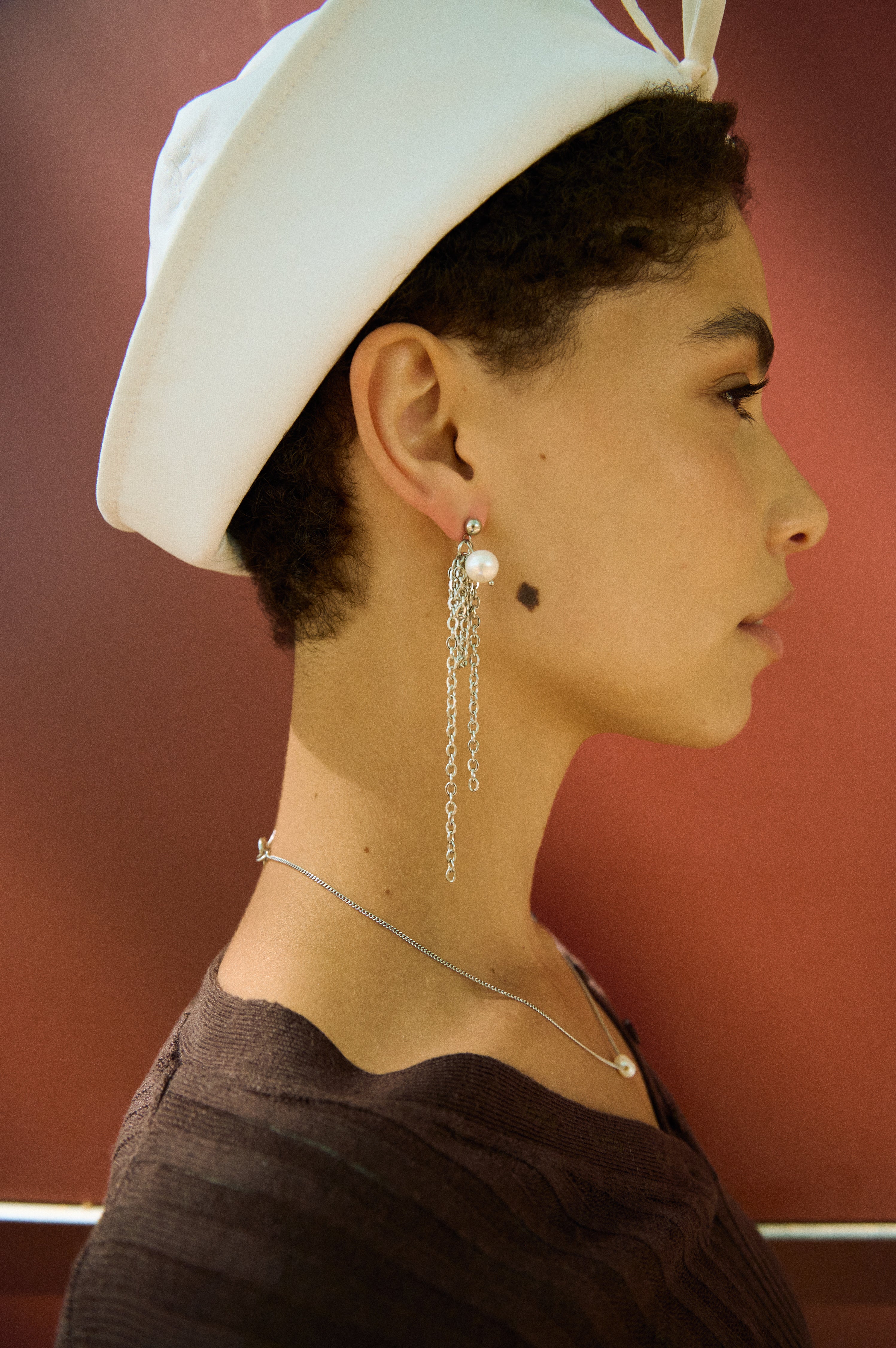 Model wearing long pearl chain drop earrings with white freshwater pearls and fine chain strands.