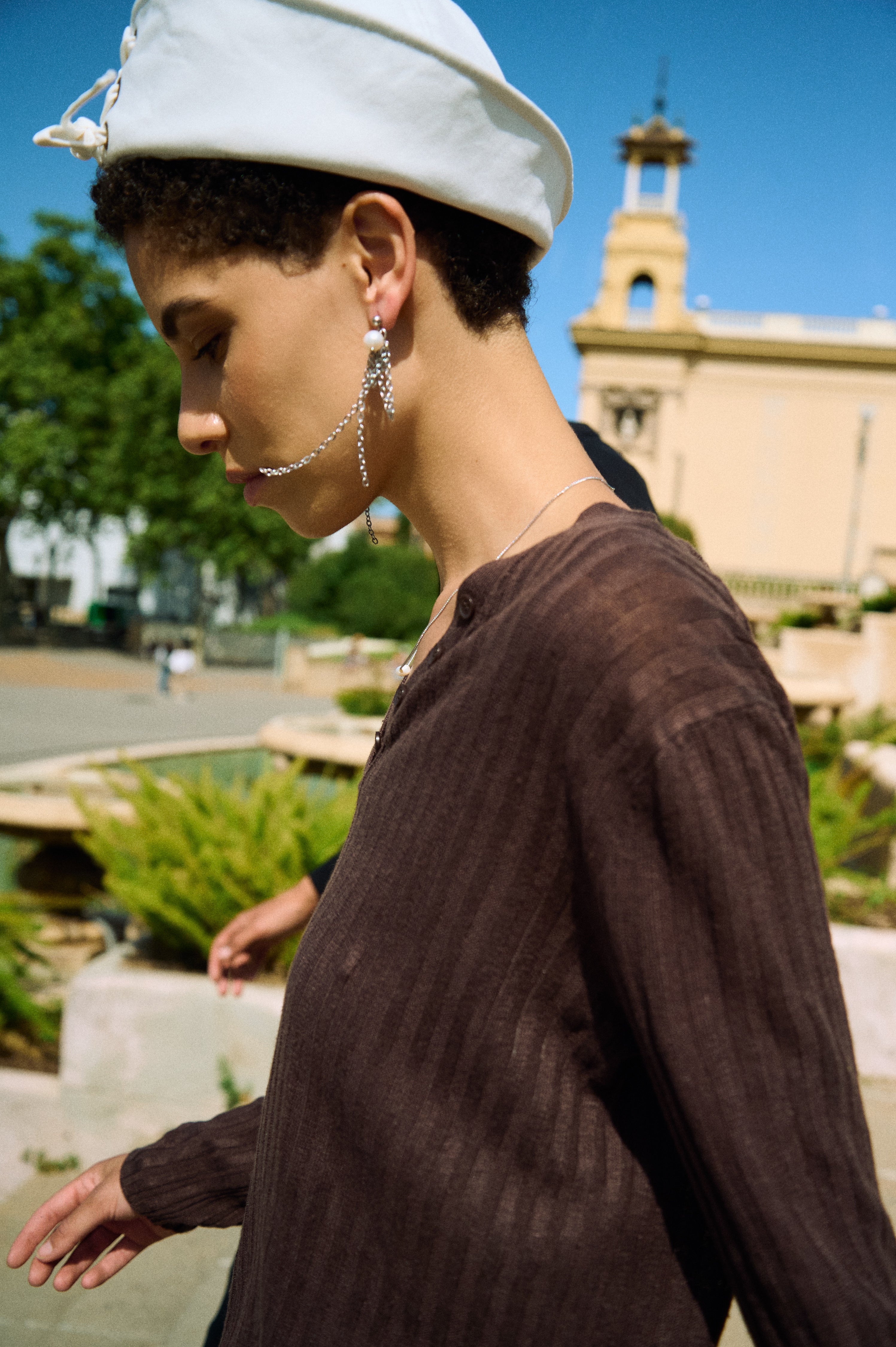 Model wearing long pearl chain drop earrings with white freshwater pearls and fine chain strands.