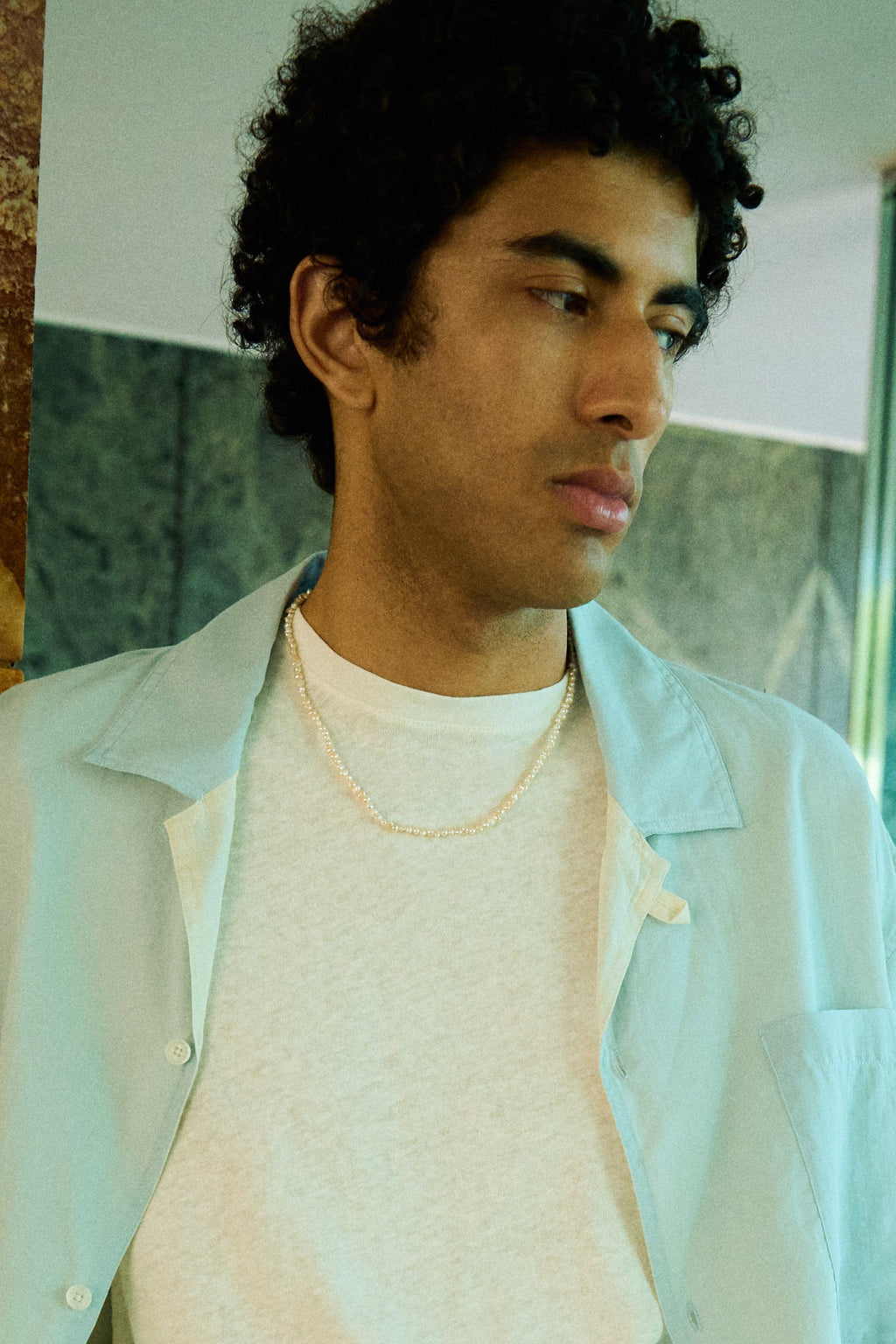 Man wearing a men’s nugget freshwater pearl necklace with small white pearls.