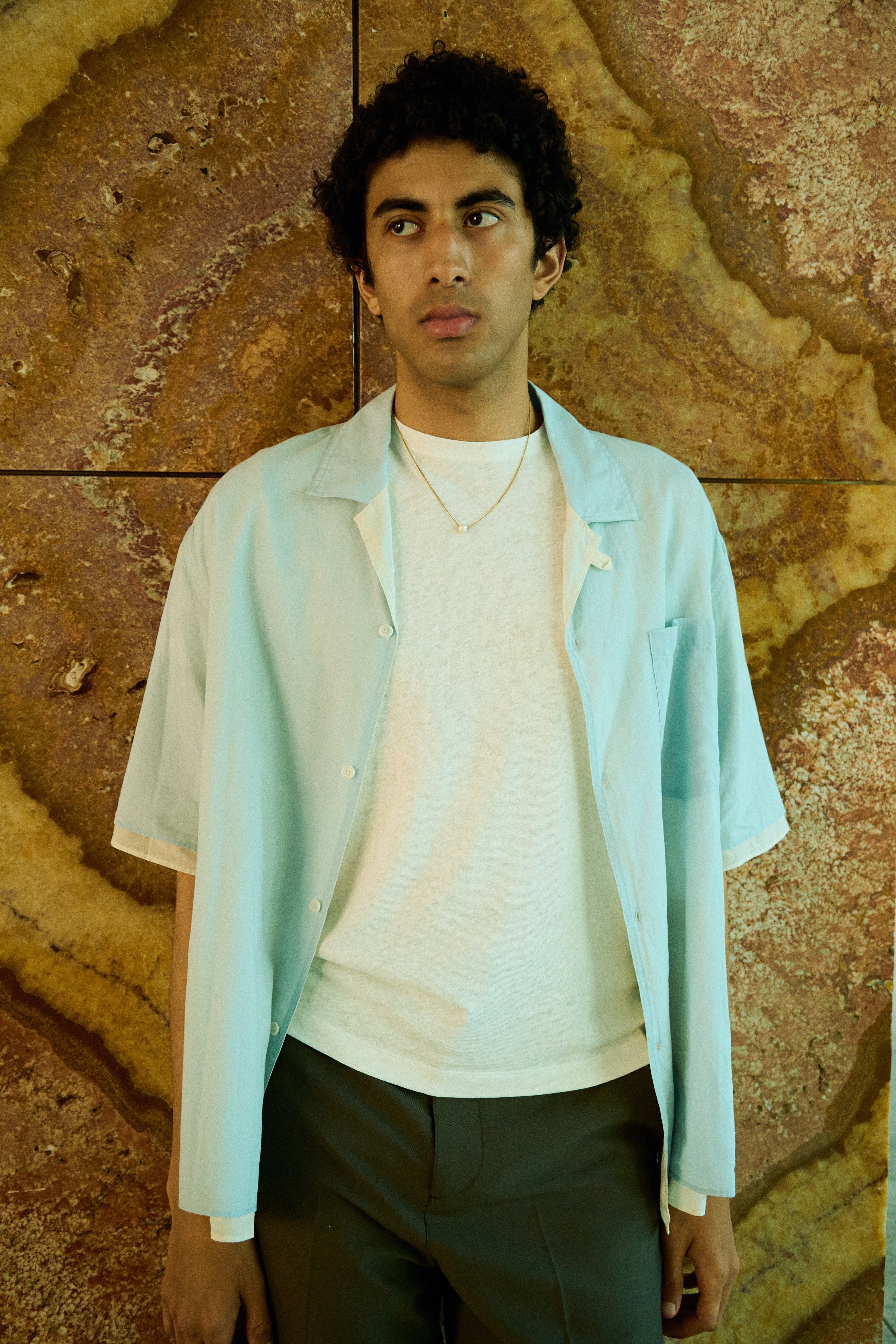 Man wearing a minimal single pearl necklace on a fine chain.