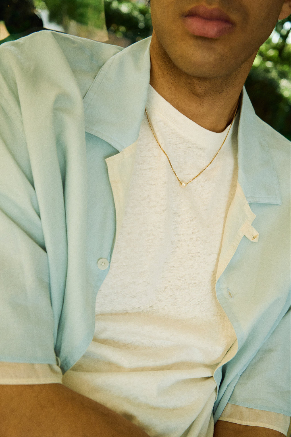 Man wearing a minimal single pearl necklace on a fine chain.