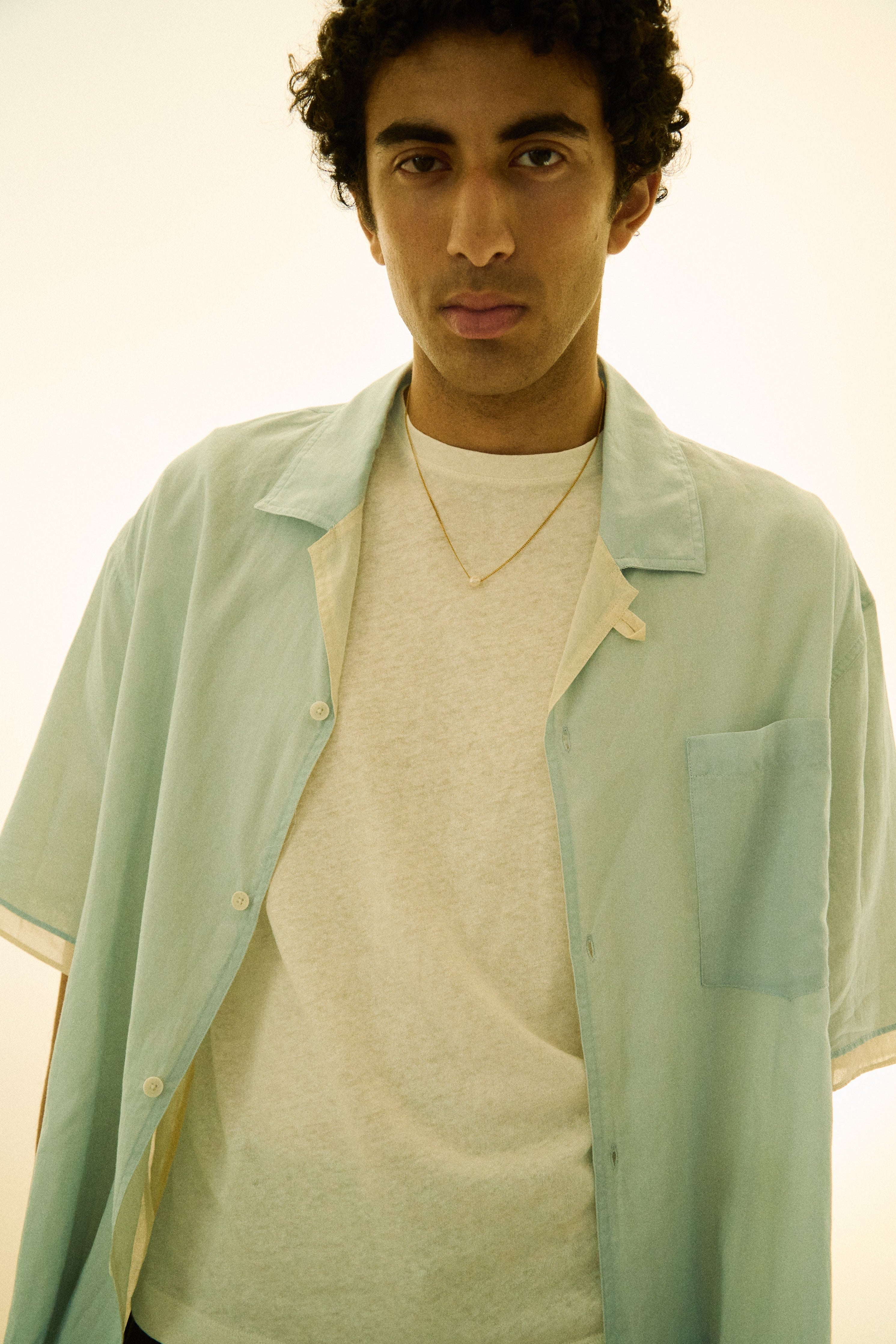 Man wearing a minimal single pearl necklace on a fine chain.