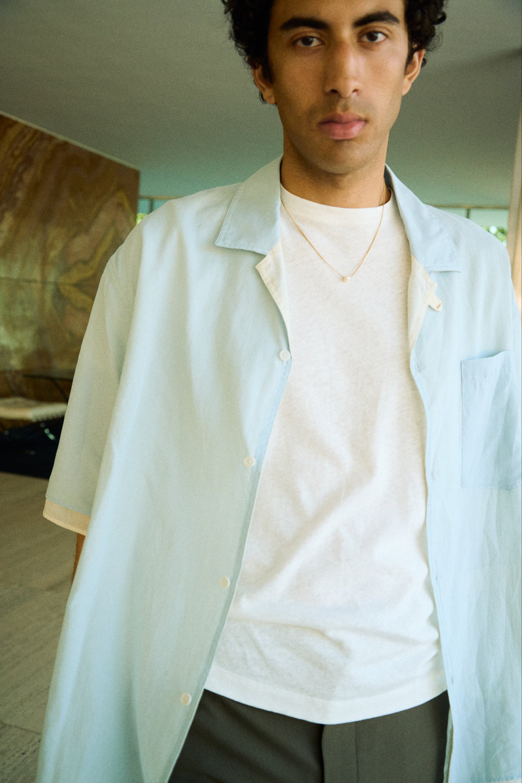 Man wearing a minimal single pearl necklace on a fine chain.