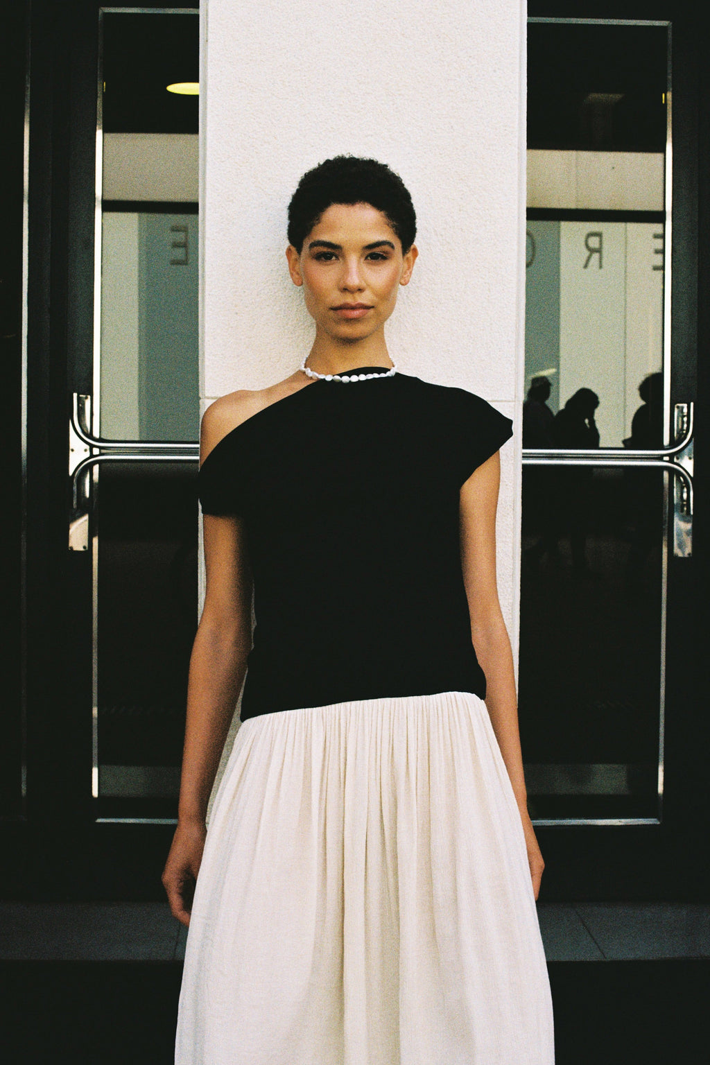 Model wearing a natural coin freshwater pearl necklace with a black top and white skirt.