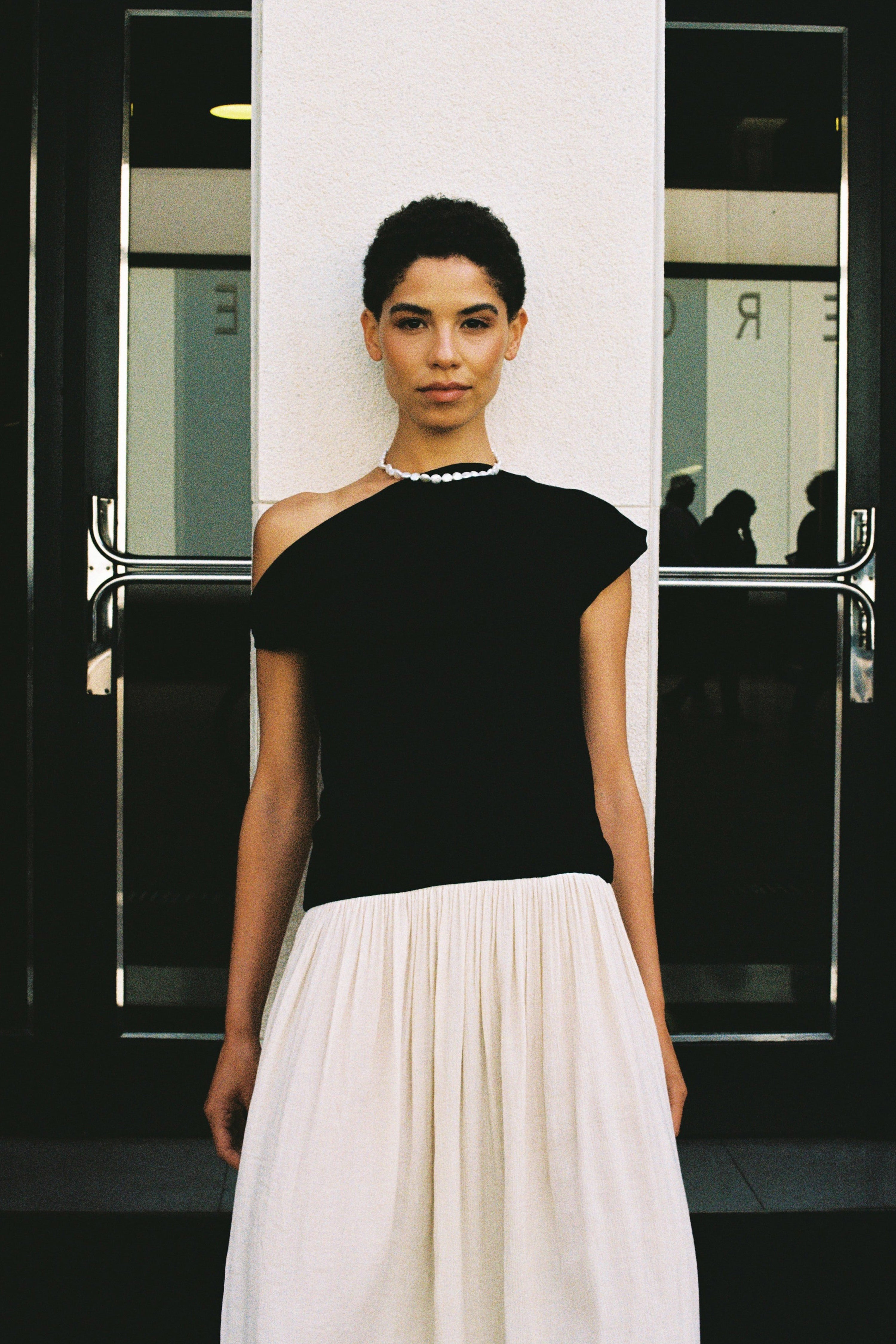 Model wearing a natural coin freshwater pearl necklace with a black top and white skirt.