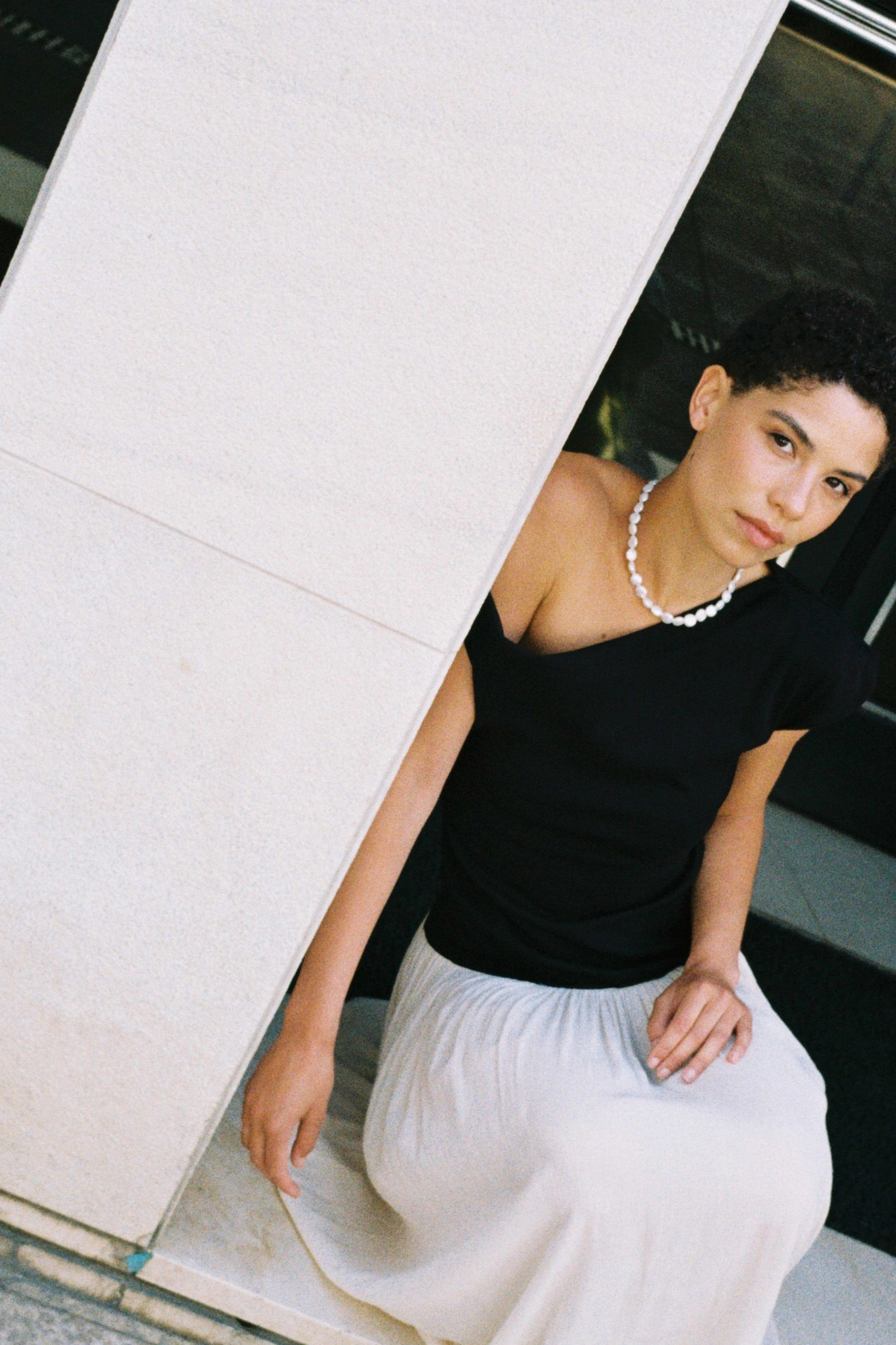 Model wearing a natural coin freshwater pearl necklace with a black top and white skirt.