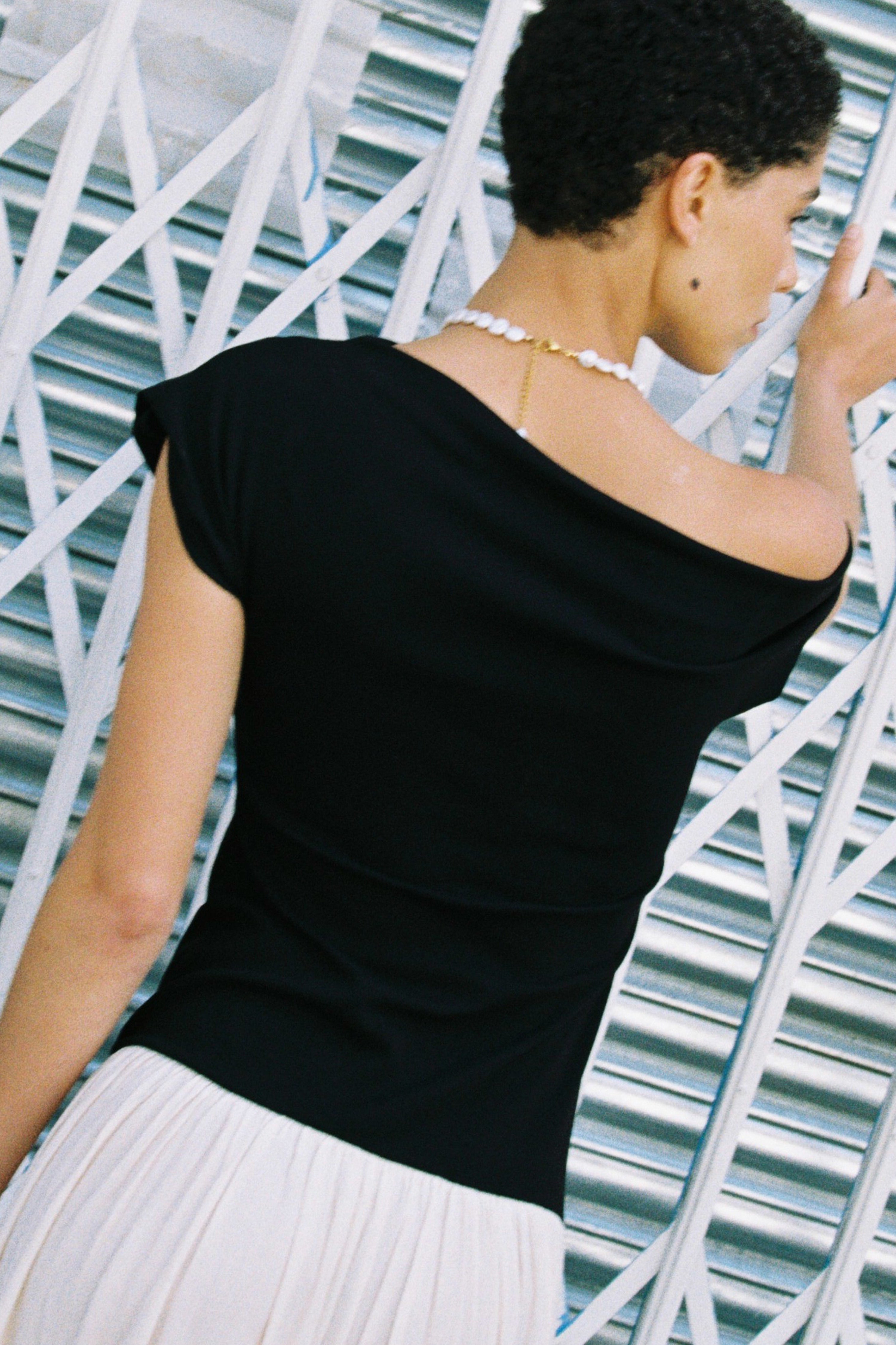 Model wearing a natural coin freshwater pearl necklace with a black top and white skirt.