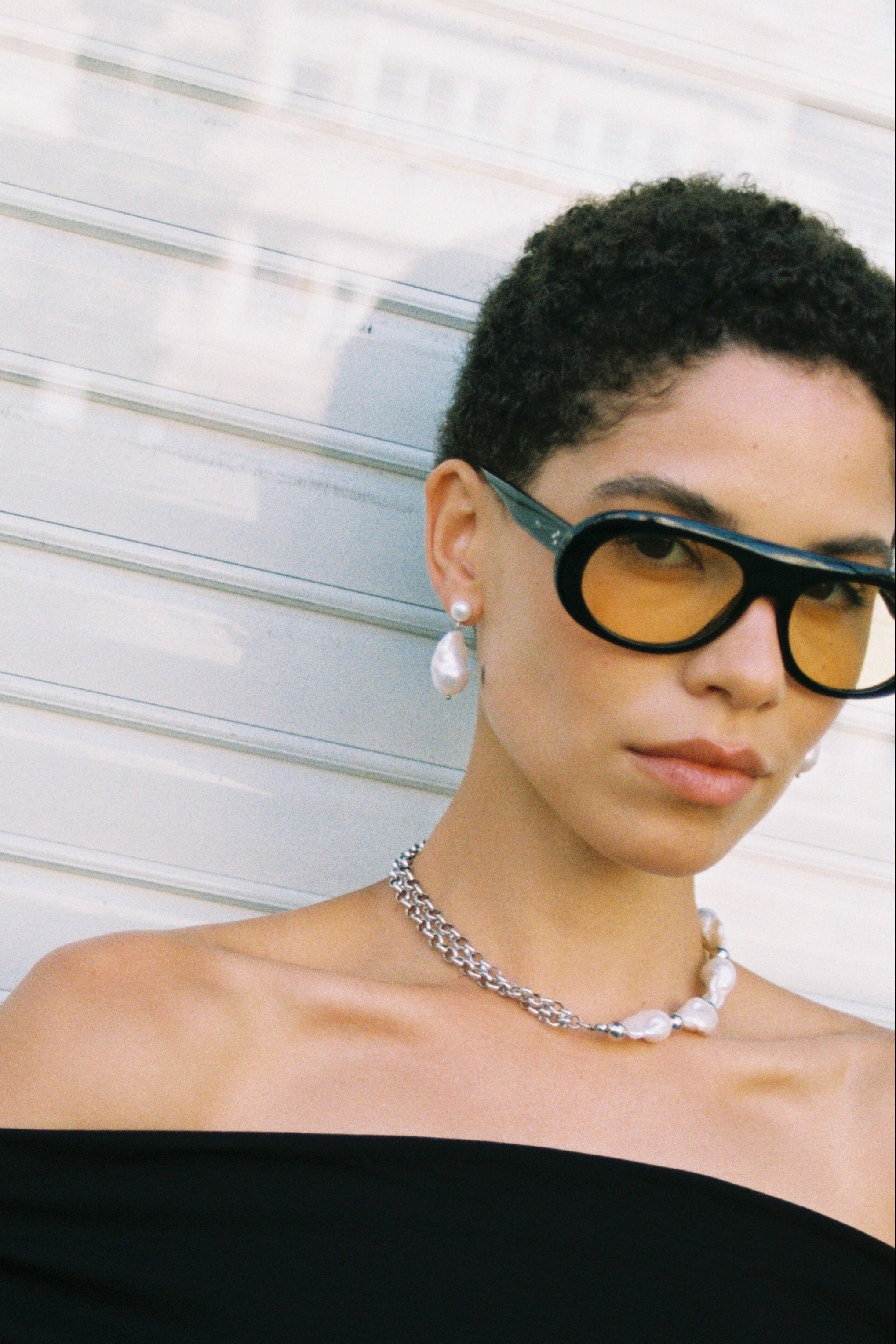 Model wearing baroque pearl drop earrings with a small button pearl and a larger freshwater pearl drop.