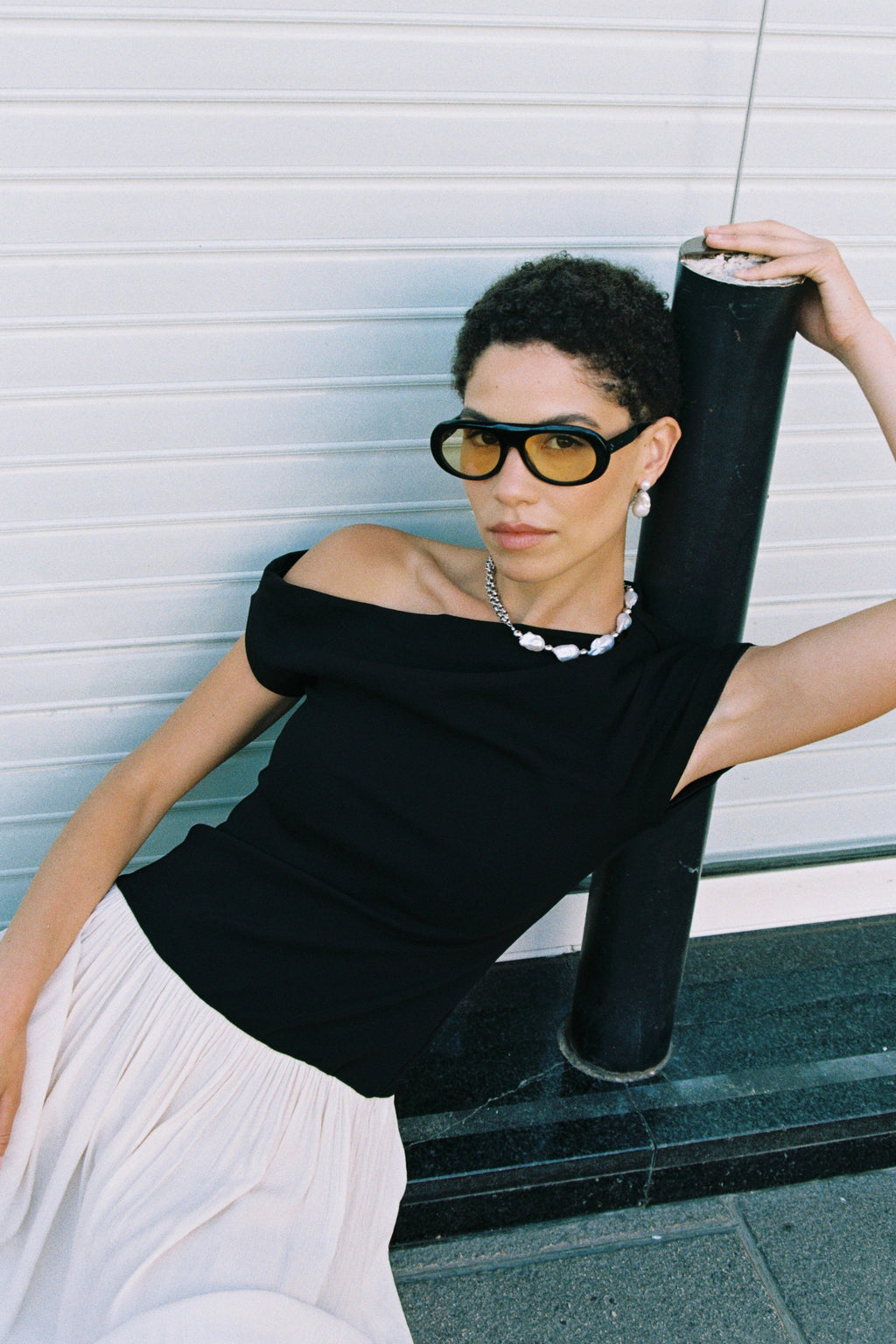 Model wearing a half double chain, half baroque freshwater pearl necklace with hand-knotted pearls and black off-shoulder top.