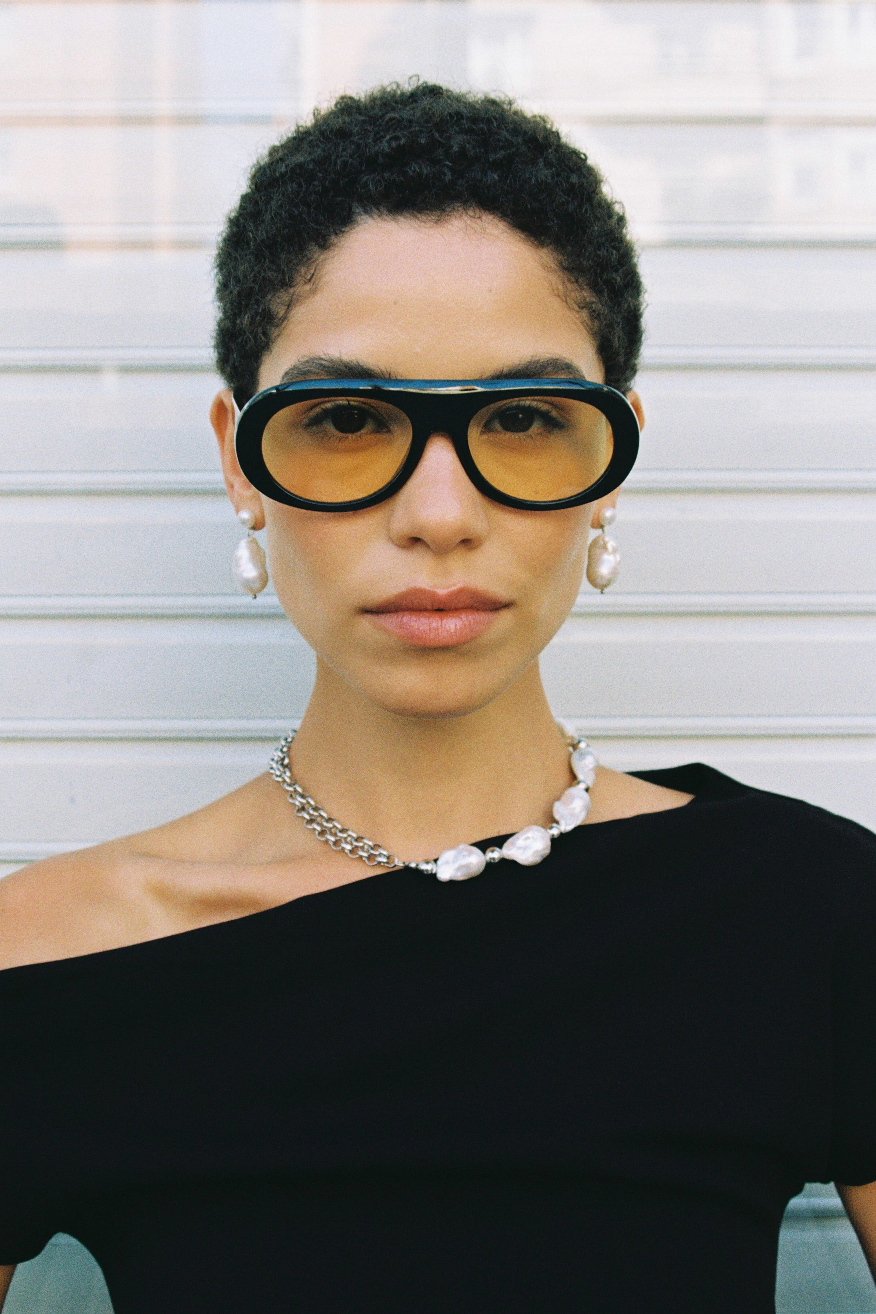 Model wearing a half double chain, half baroque freshwater pearl necklace with hand-knotted pearls and black off-shoulder top.