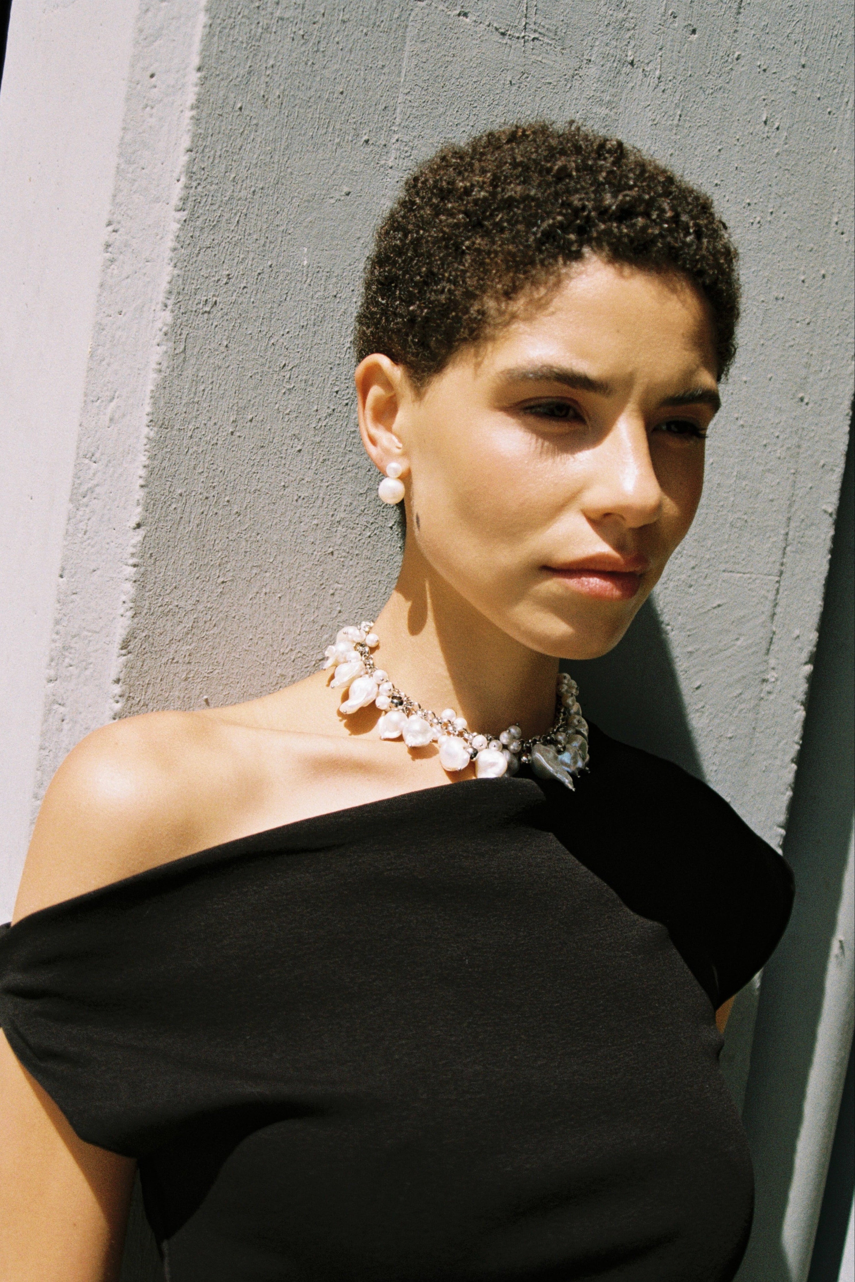 Model wearing double pearl stud earrings made from two natural freshwater pearls.