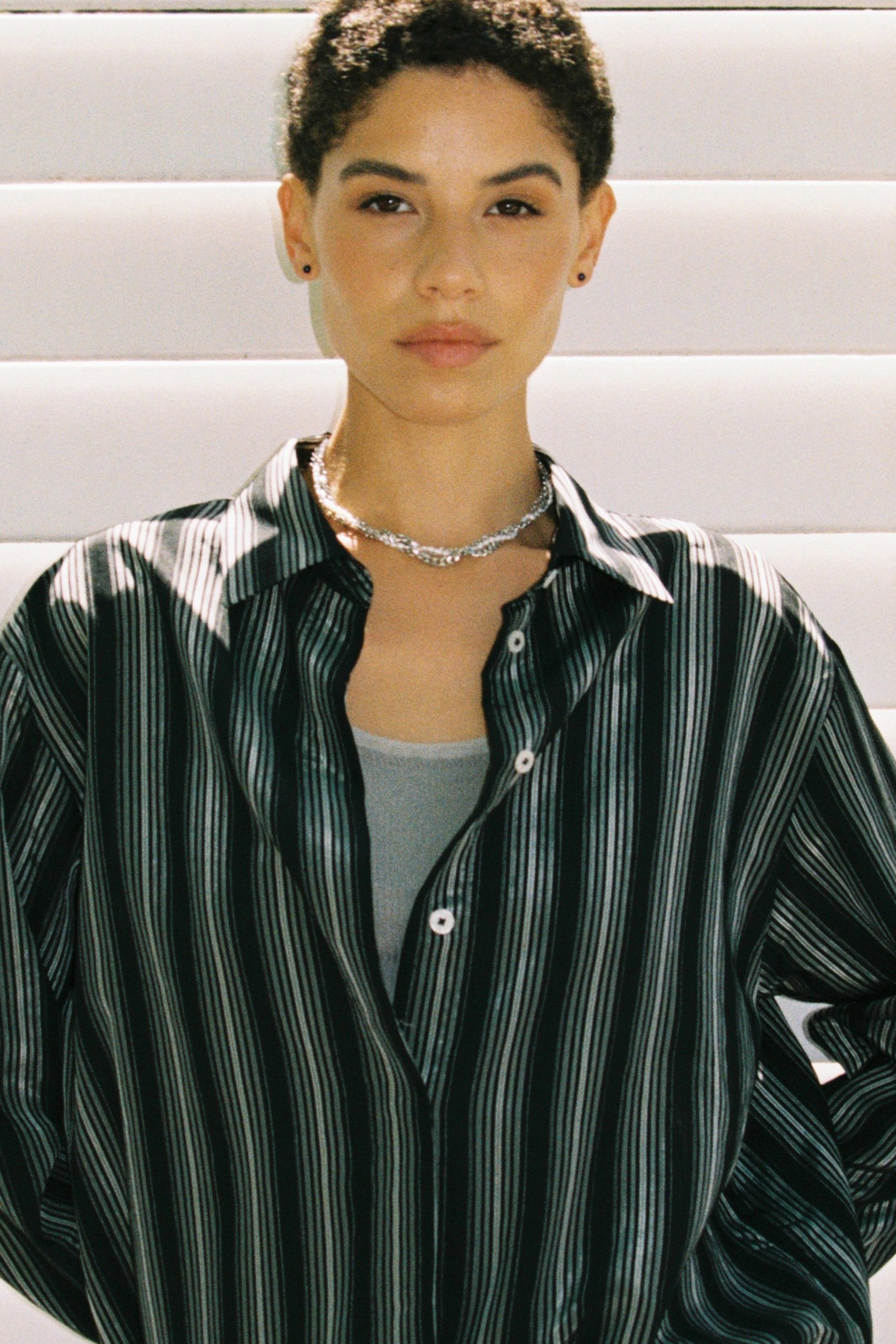 Model wearing minimal dark blue freshwater pearl stud earrings.