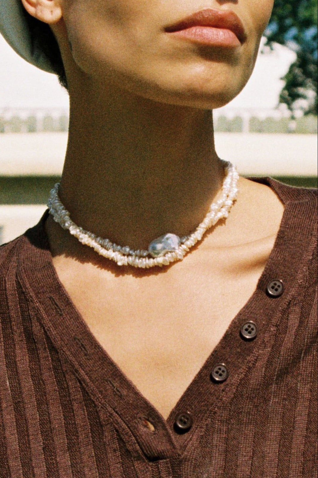 Model wearing a baroque keshi pearl necklace with white keshi pearls and a central baroque pearl.