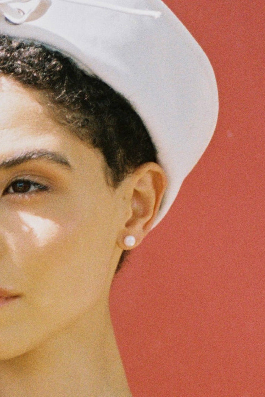 Model wearing white button freshwater pearl stud earrings.